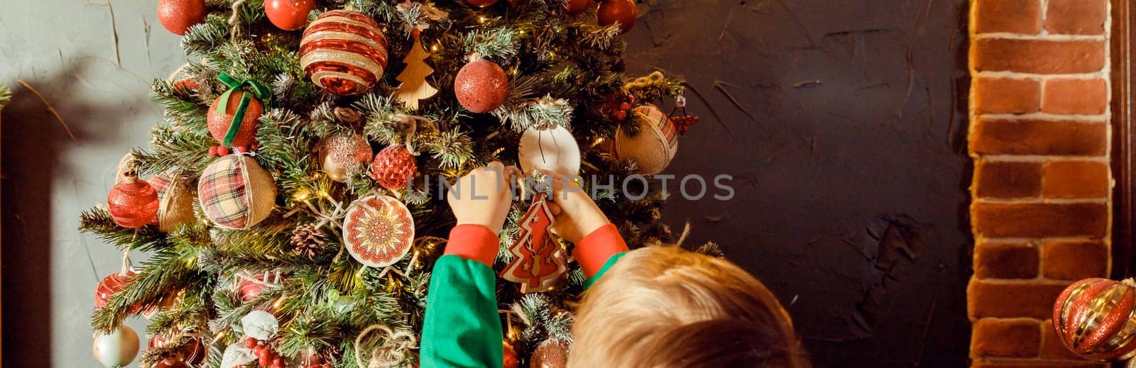 Close up of little Caucasian girl's hands putting ornaments on Christmas tree styled in blue and grey