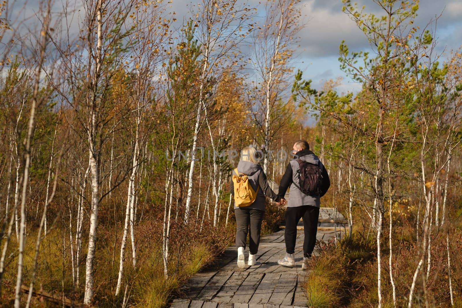 Two tourists walk along a wooden path in a swamp in Yelnya, Belarus.