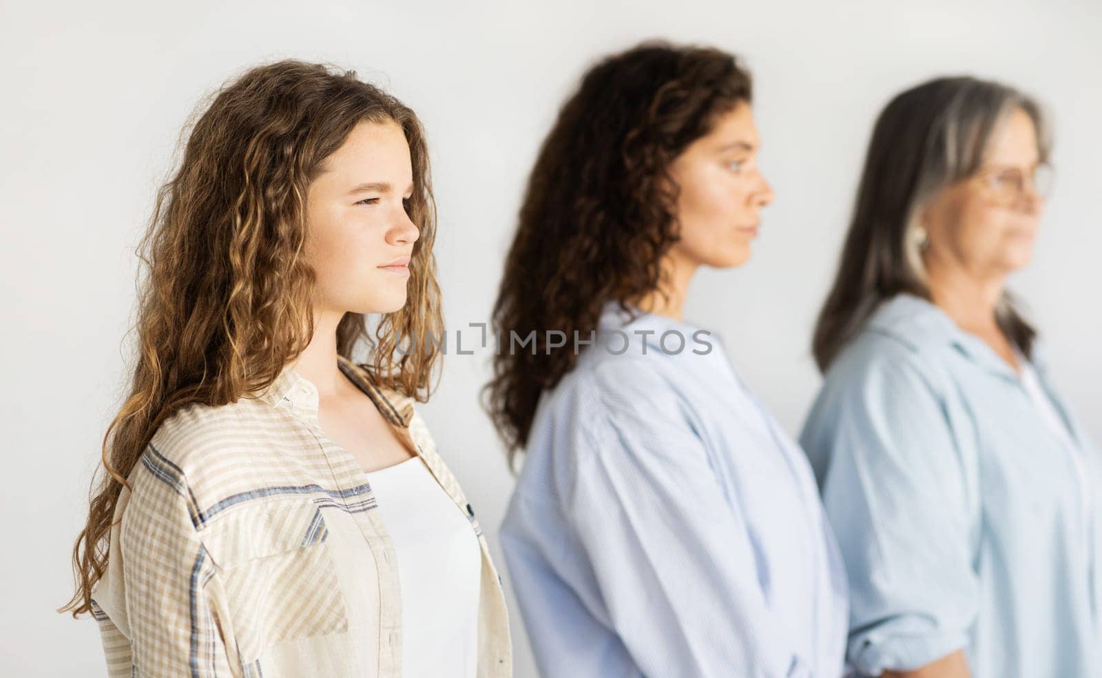 Calm serious caucasian teen girl, millennial mom and old grandmother, isolated on white studio background. Female generation, genetic, love, relationship and family, beauty care, lifestyle