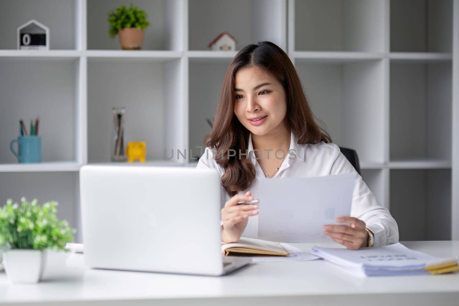 Young beautiful business woman using laptop and checking documents while working on laptop.