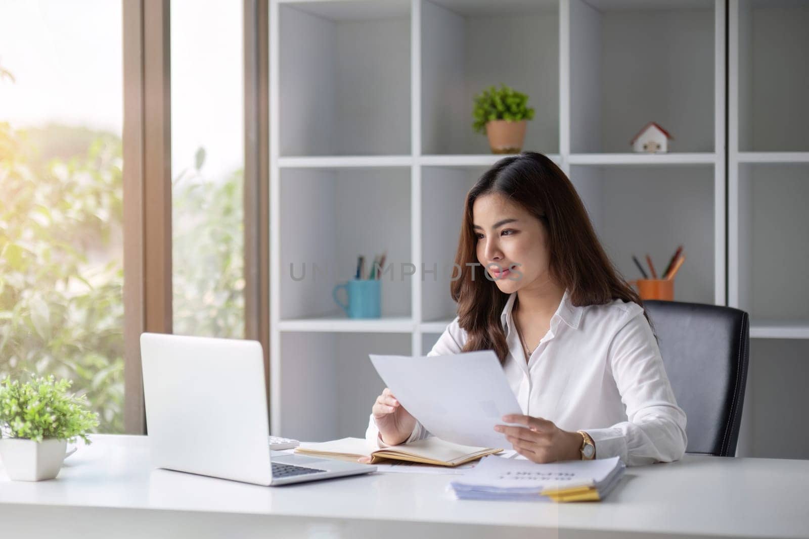 Young beautiful business woman using laptop and checking documents while working on laptop.