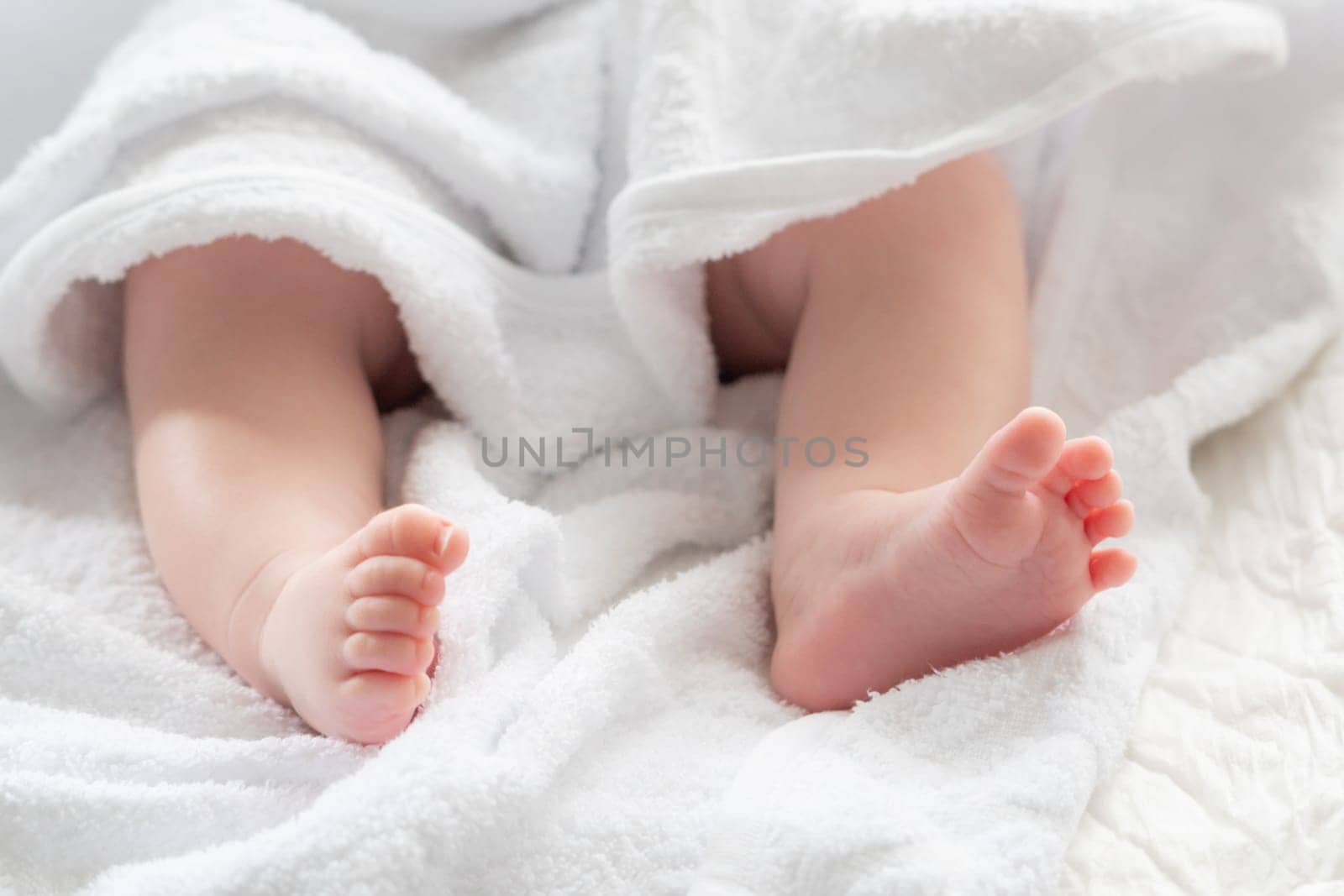 A baby's feet, representing the pure start of a life journey, subtly peek out from the comforting embrace of a white towel, symbolizing protection and care