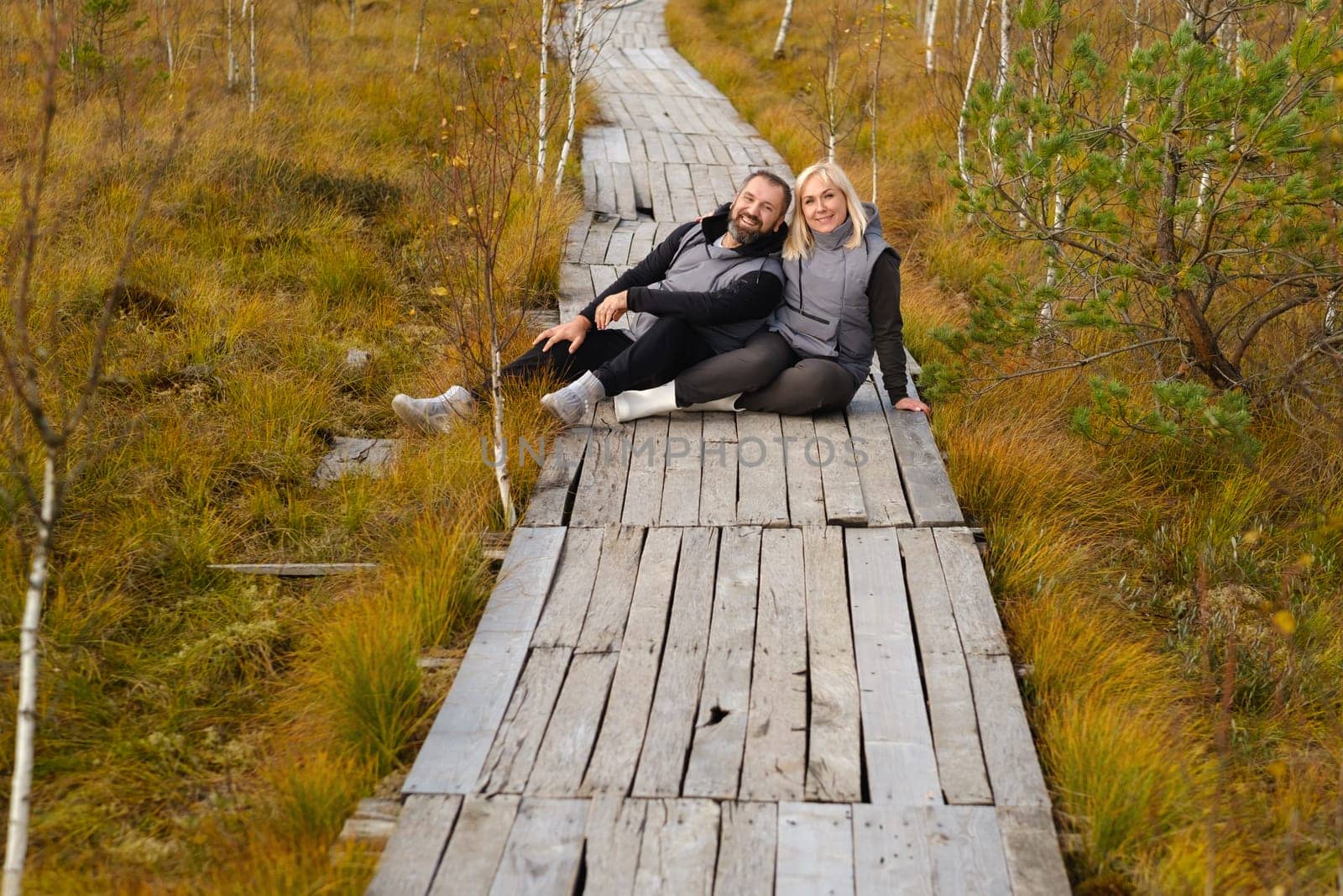 A couple sits on a wooden path in a swamp in Yelnya, Belarus.