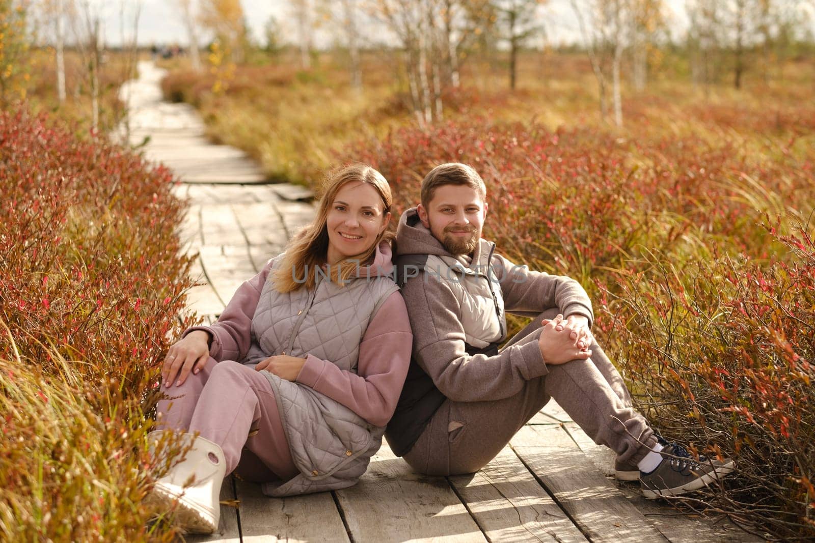 A couple sits on a wooden path in a swamp in Yelnya, Belarus.