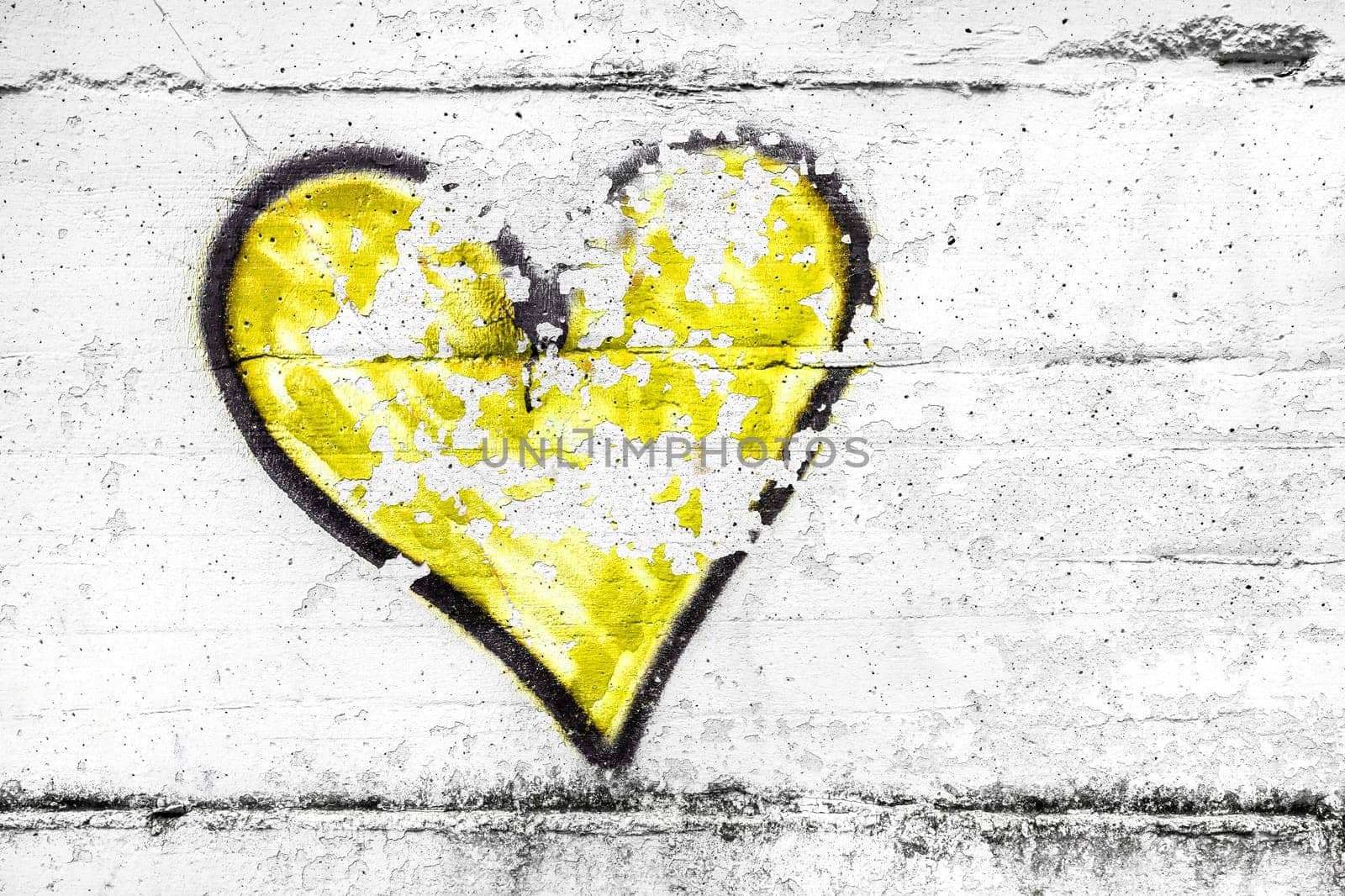 Painted yellow abstract heart shape love symbol, dirty wall background, metaphor to urban and romantic valentine, grunge style.