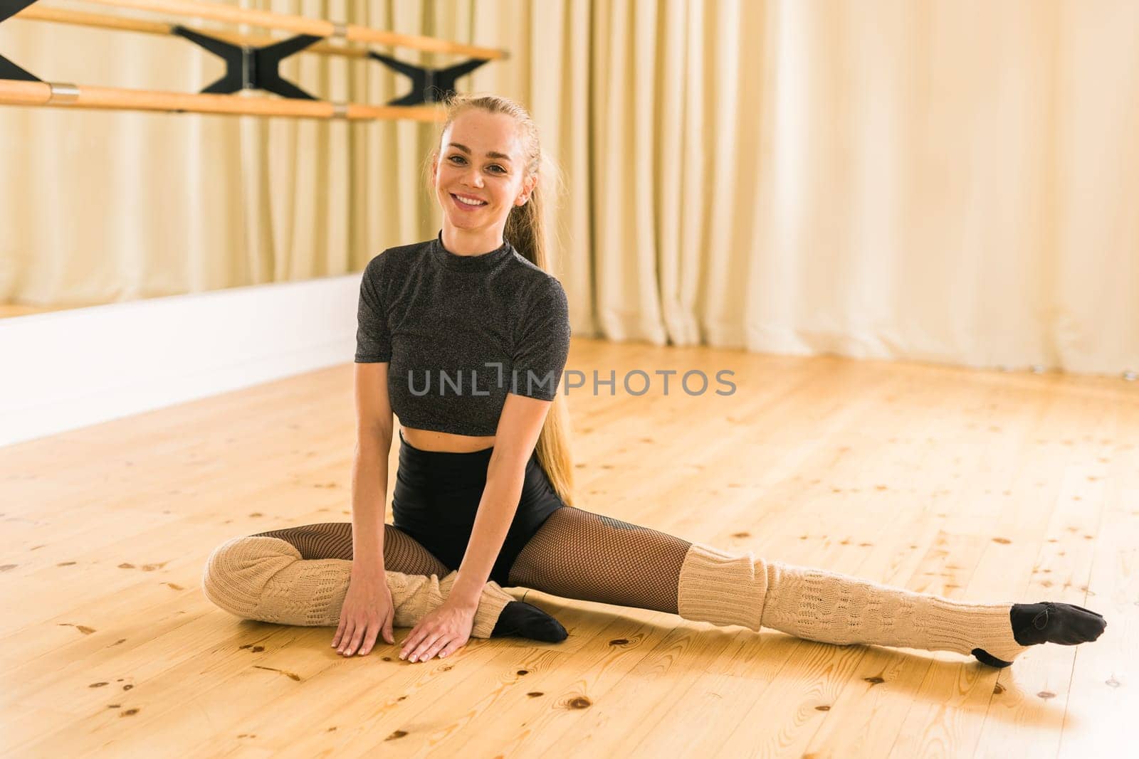 Young slim woman is doing some twine to stretch. Joyful talented woman in fitness class by Satura86