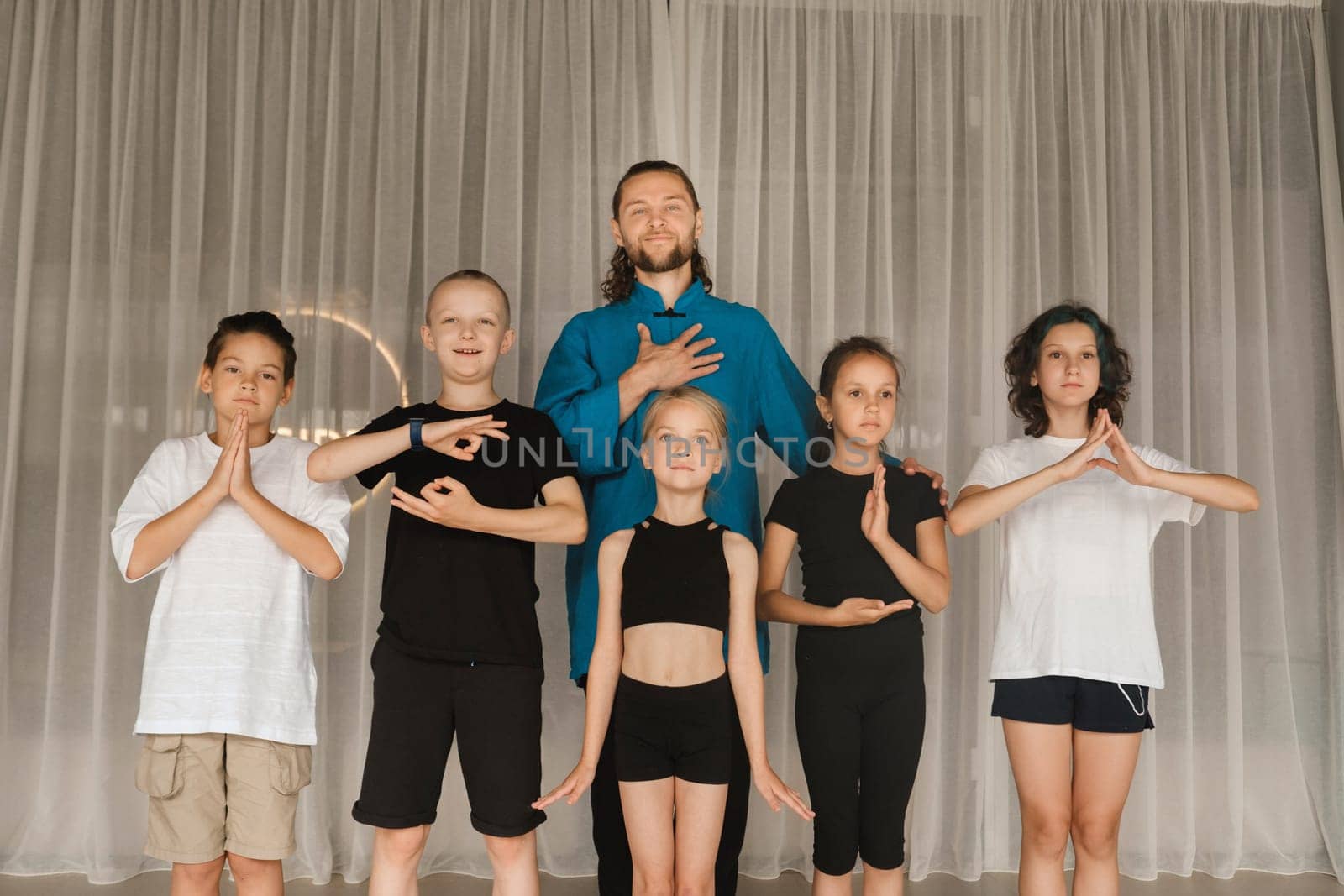 A joint portrait of a yoga coach and children standing in a fitness room by Lobachad