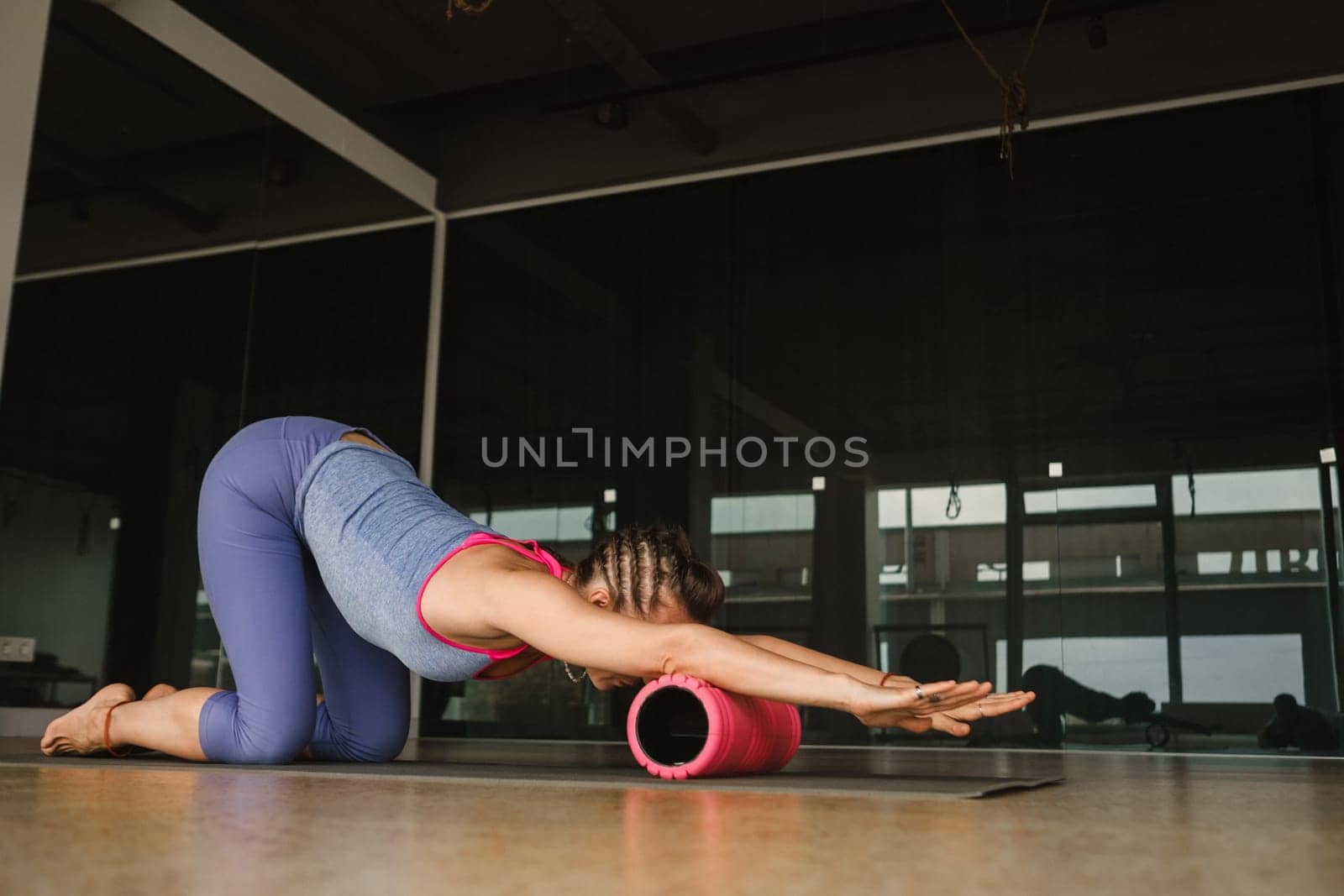 Slender girl doing yoga with a big massage roller on the floor by Lobachad