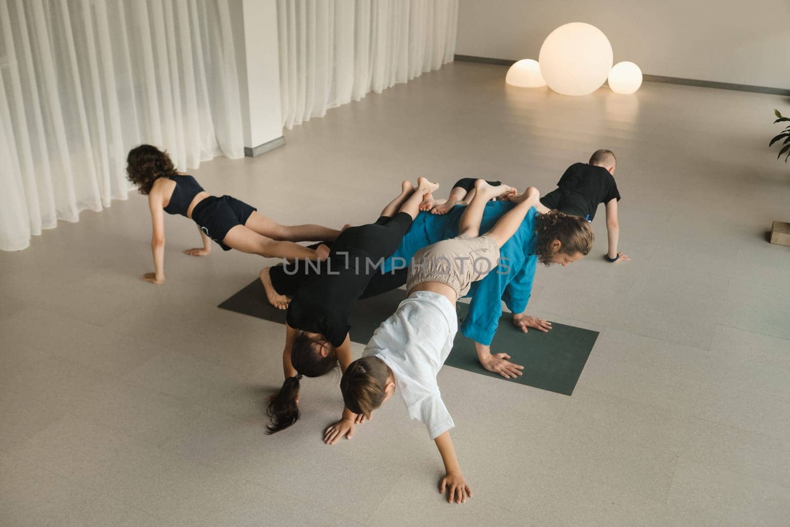A team of children and a coach do an unusual pose at an indoor yoga workout.