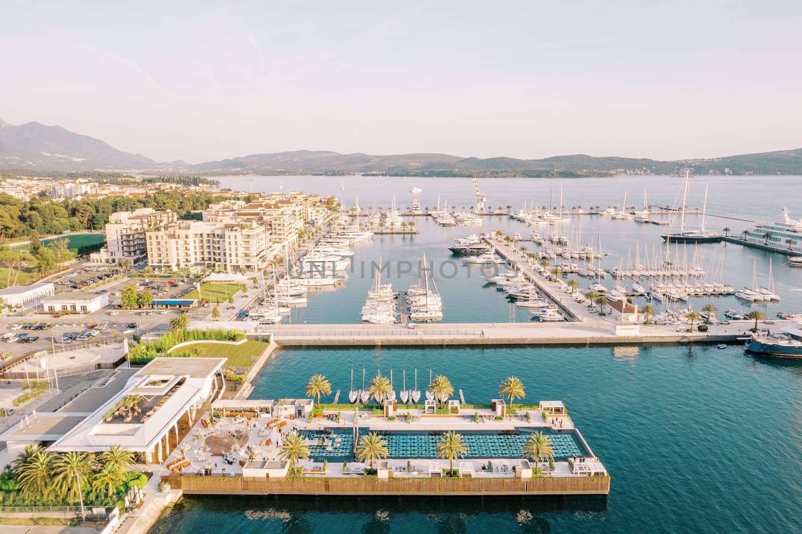Swimming pool on a wide dock with moored yachts of a luxurious marina. Porto, Montenegro. Drone. High quality photo