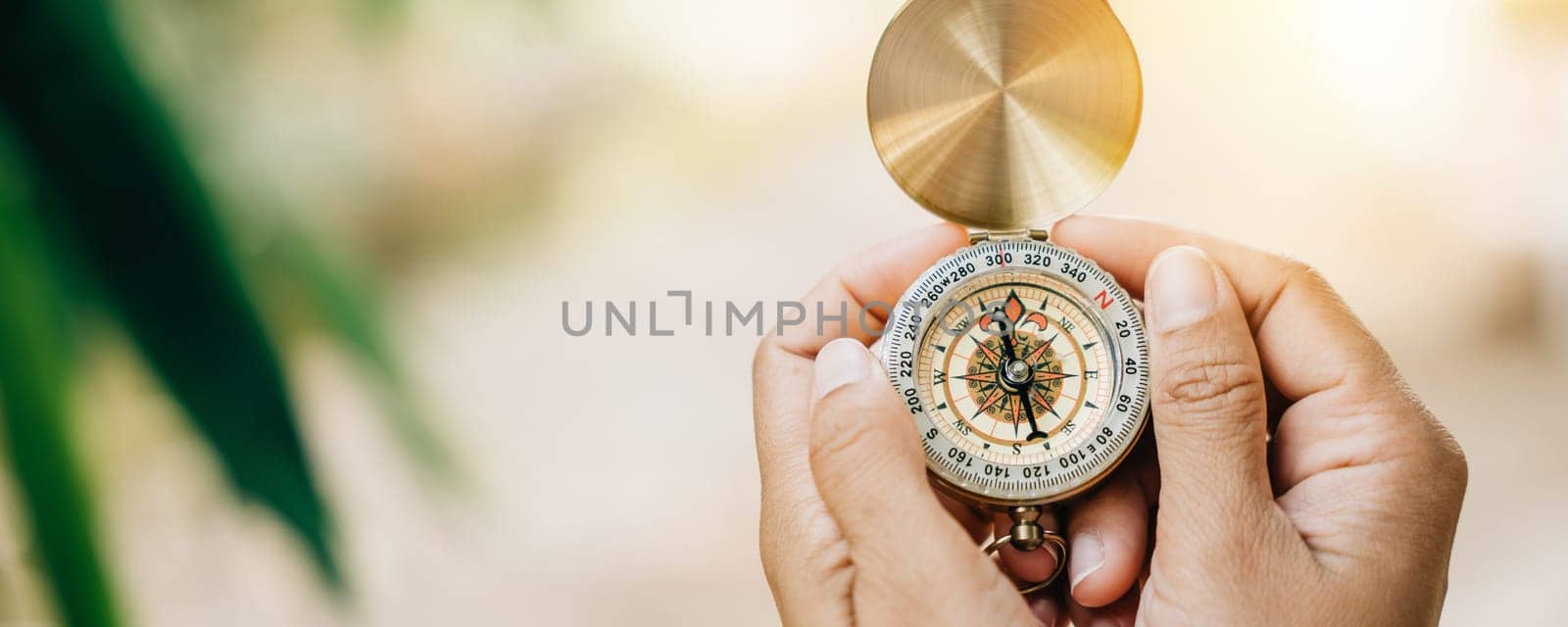 In a close-up shot a woman uses a compass in the forest. Her hand holds the compass representing guidance and exploration.