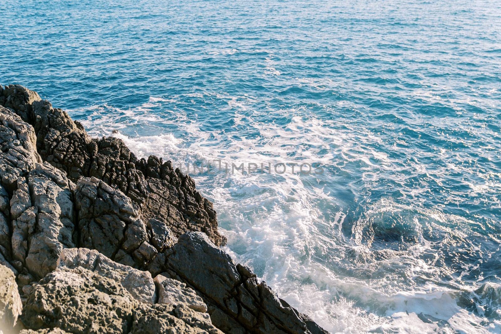 Blue sea foams hitting the rocky high shore. High quality photo