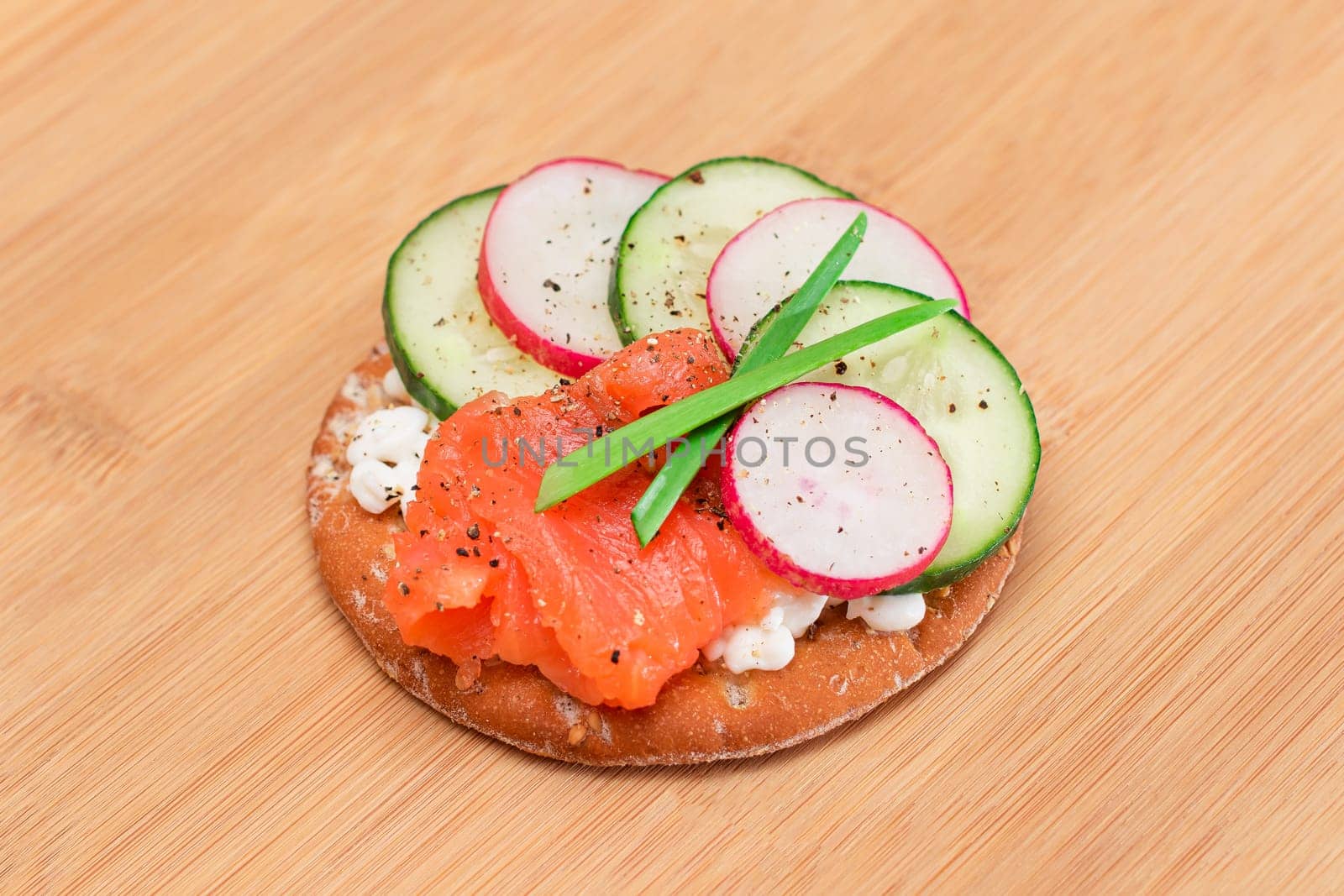 Crispy Cracker Sandwich with Salmon, Cucumber, Radish, Cottage Cheese and Green Onions on Bamboo Cutting Board. Easy Breakfast. Quick and Healthy Sandwiches. Crispbread with Tasty Filling