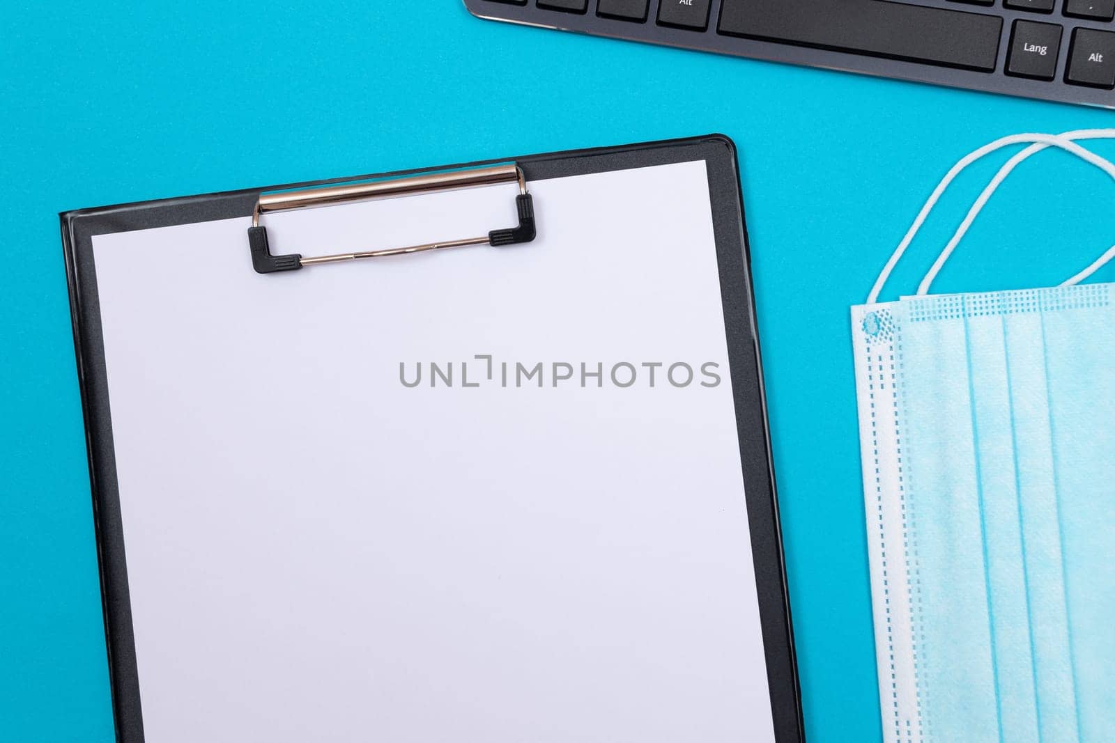 Black Clipboard with Blank White Sheet of Paper Lying on Blue Table - Top View, Flat Lay