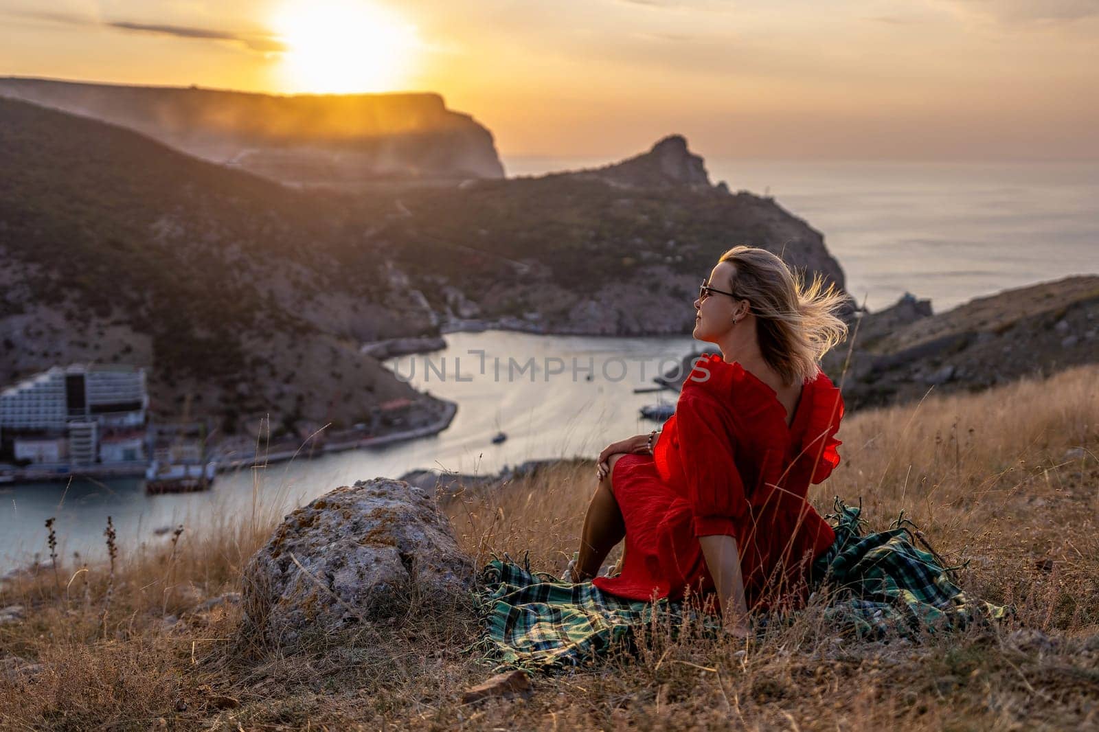 Woman sunset sea mountains. Happy woman siting with her back on the sunset in nature summer posing with mountains on sunset, silhouette. Woman in the mountains red dress, eco friendly, summer landscape active rest by Matiunina