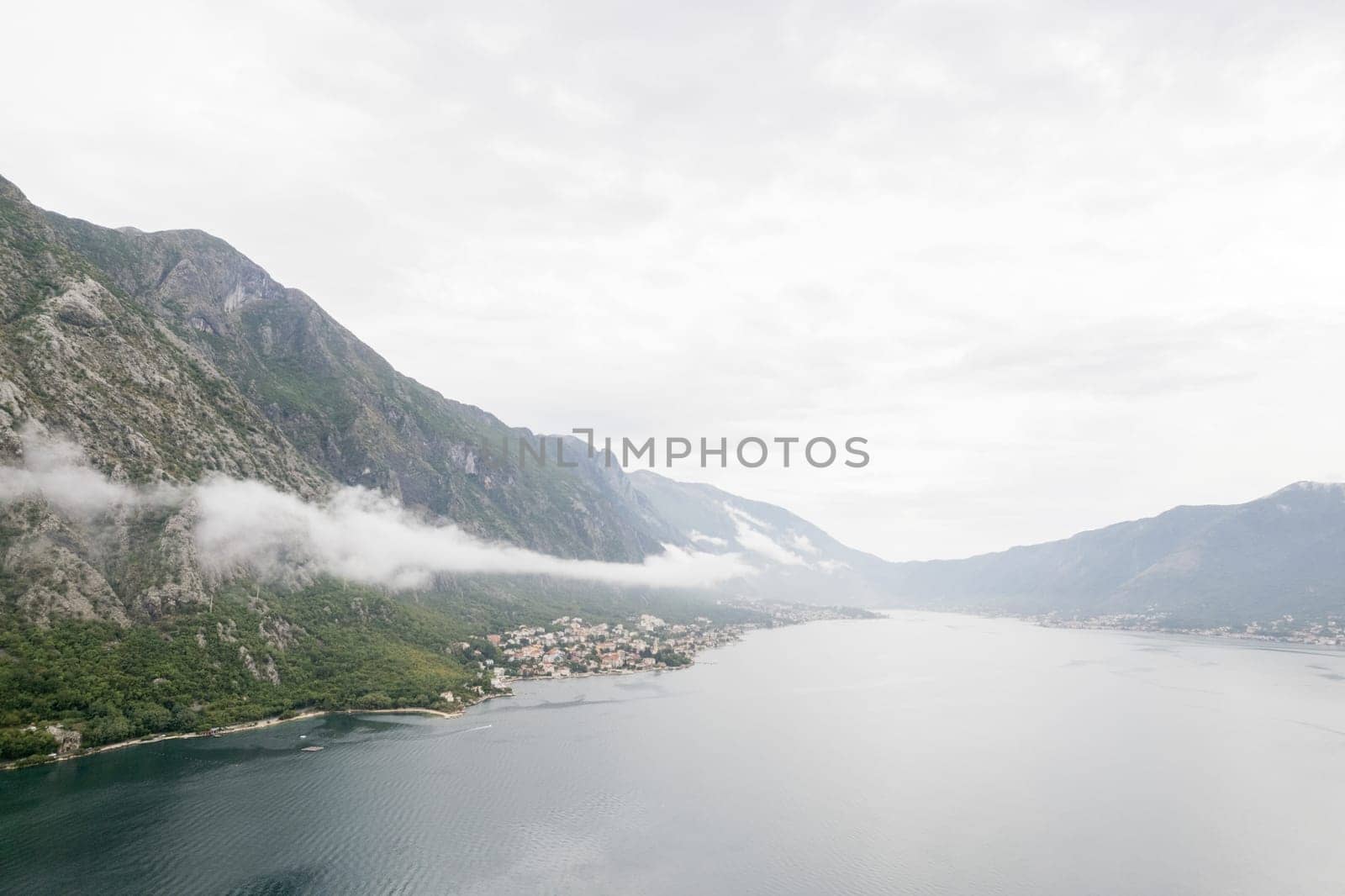 Fog descends in waves from the mountain ridge to the Bay of Kotor. Montenegro. Drone. High quality photo