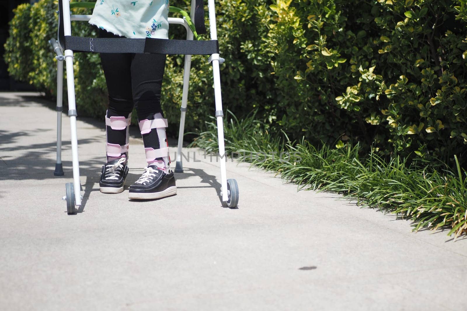 child with walking frame and knee orthosis outdoor .