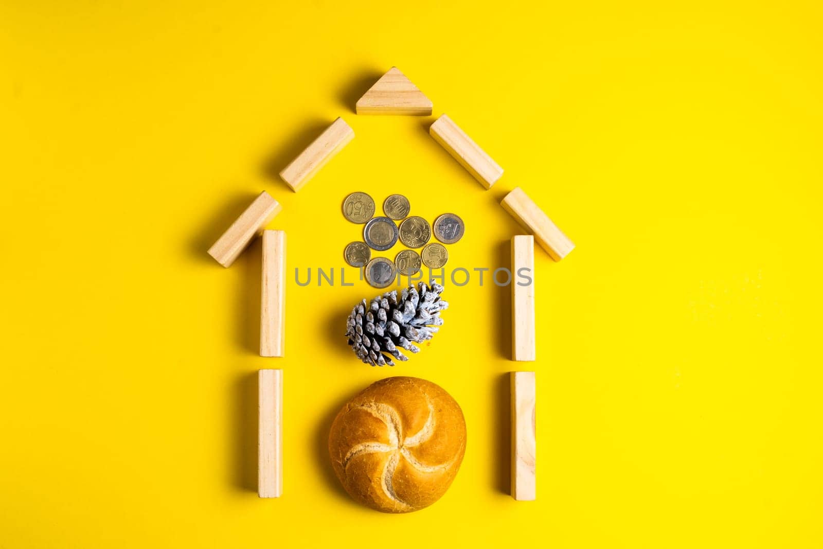 Hand holding money coins close to bread on yellow background by Zelenin