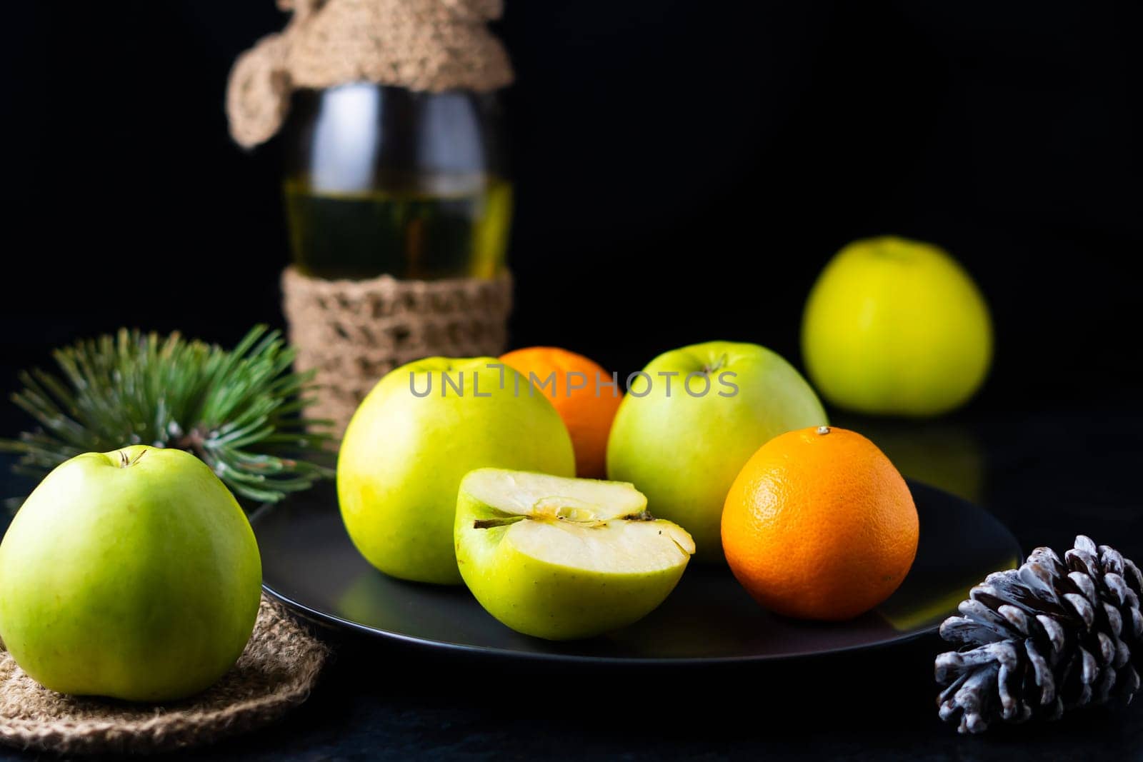 Green apples tangerines and pine cones on the table, dark background by Zelenin