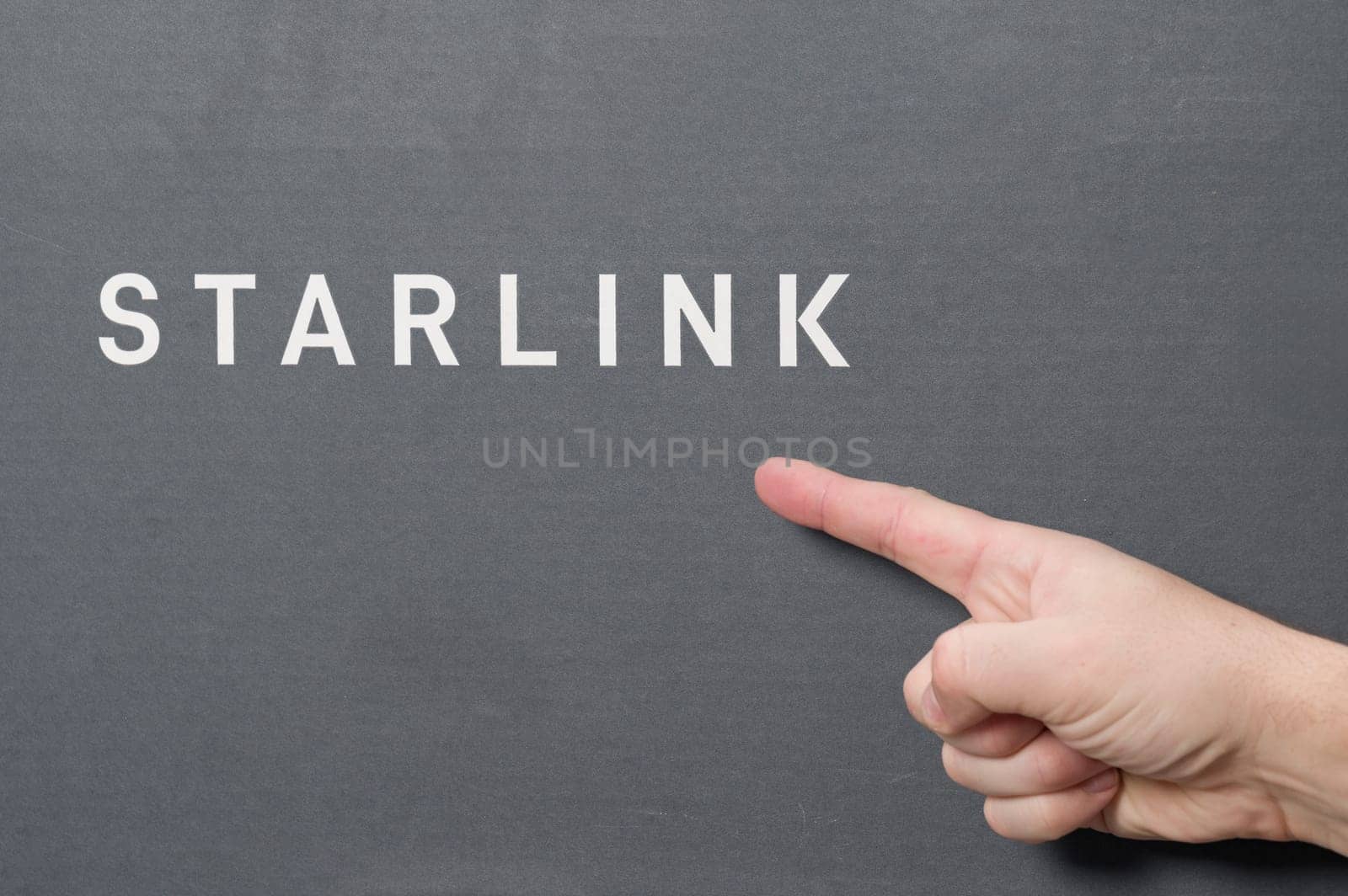 Ivano-Frankivsk, Ukraine December 2, 2023: Starlink antenna box with logo, man pointing with index finger to SpaceX company logo. by Niko_Cingaryuk