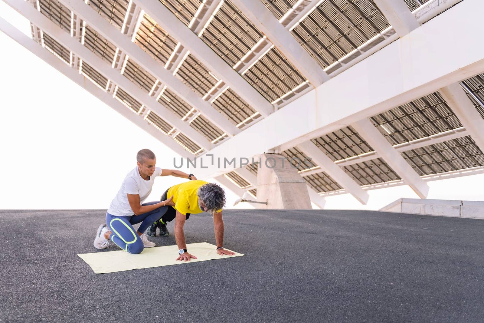 female personal trainer helping a senior sports man to do push ups correctly, concept of active and healthy lifestyle in middle age, copy space for text