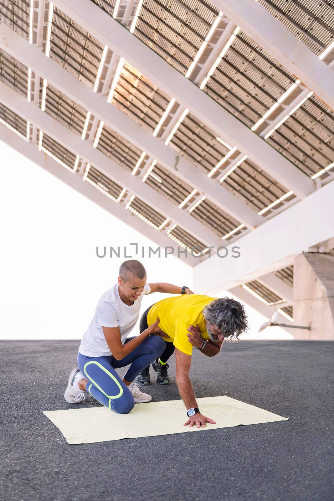 female personal trainer assisting a senior sports man to do push ups correctly, concept of active and healthy lifestyle in middle age, copy space for text