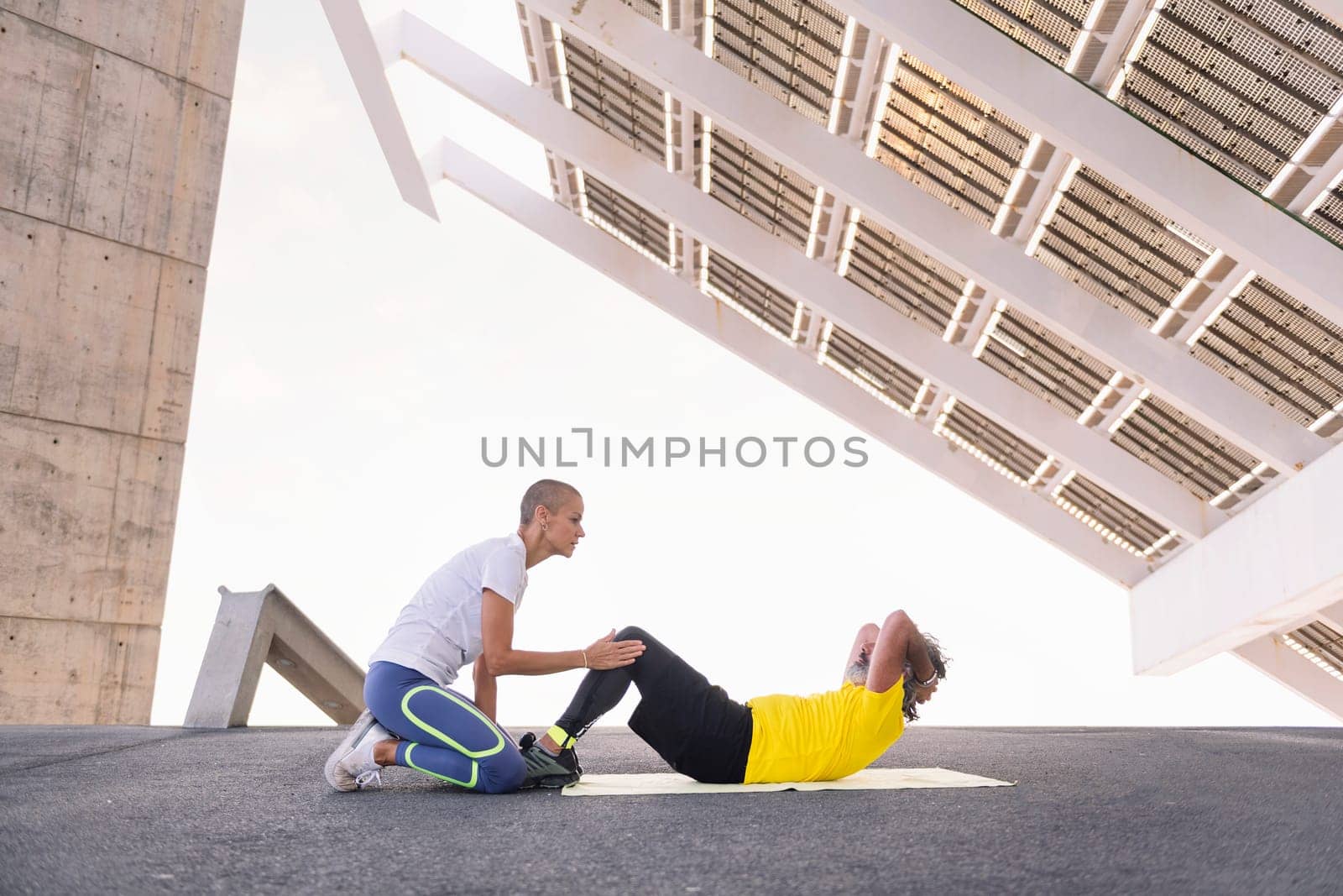 female personal trainer helping a senior sports man with abs workout, concept of active and healthy lifestyle in middle age, copy space for text