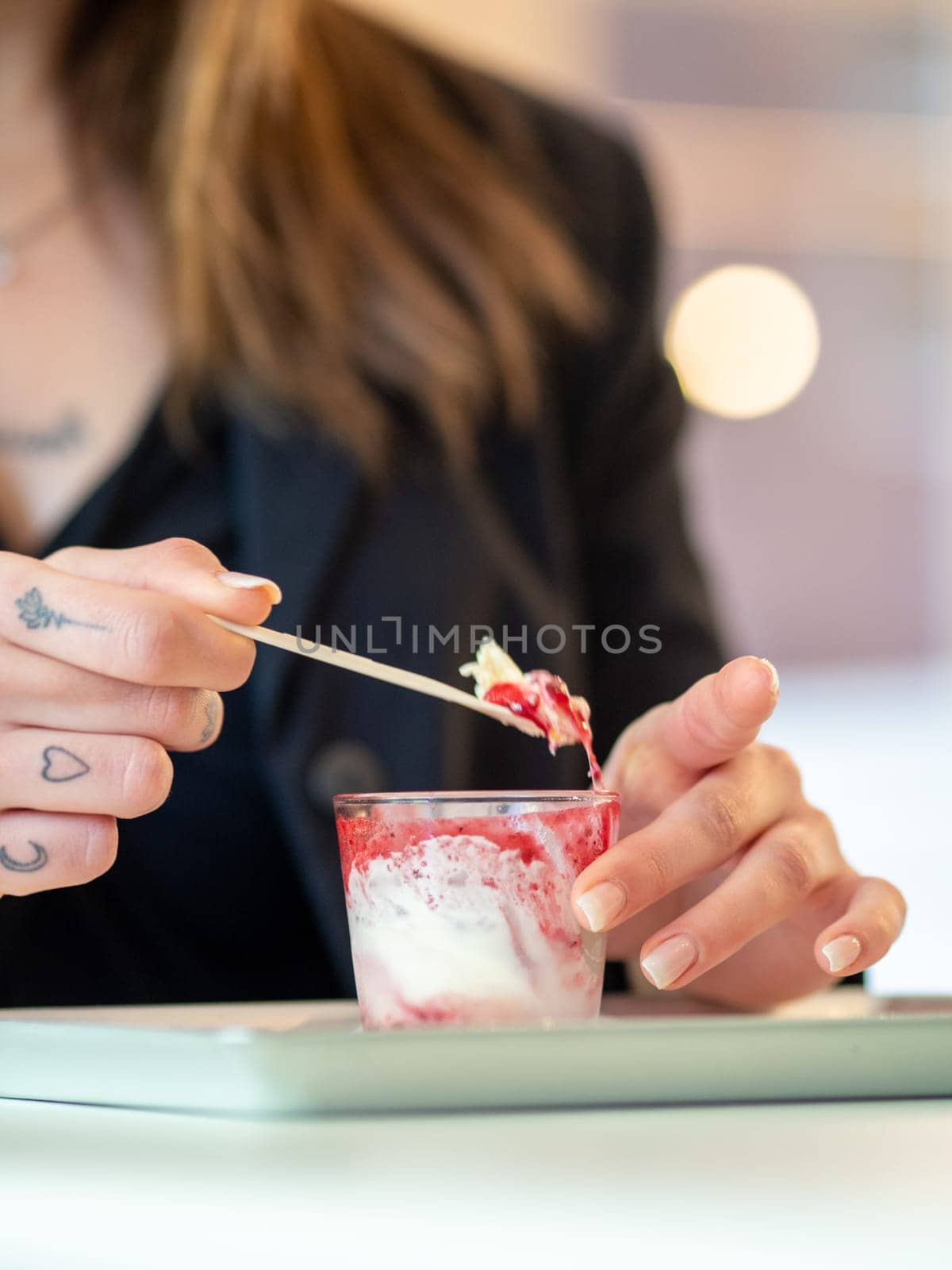 unrecognizable woman eating dessert ice cream at bistro by verbano
