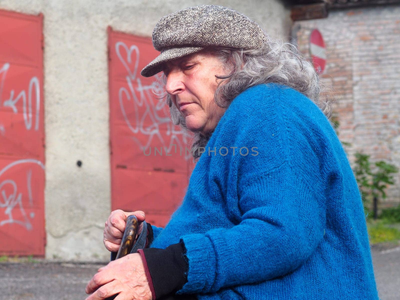 senior woman resting holding a walking street cane suffering parkinson illness by verbano