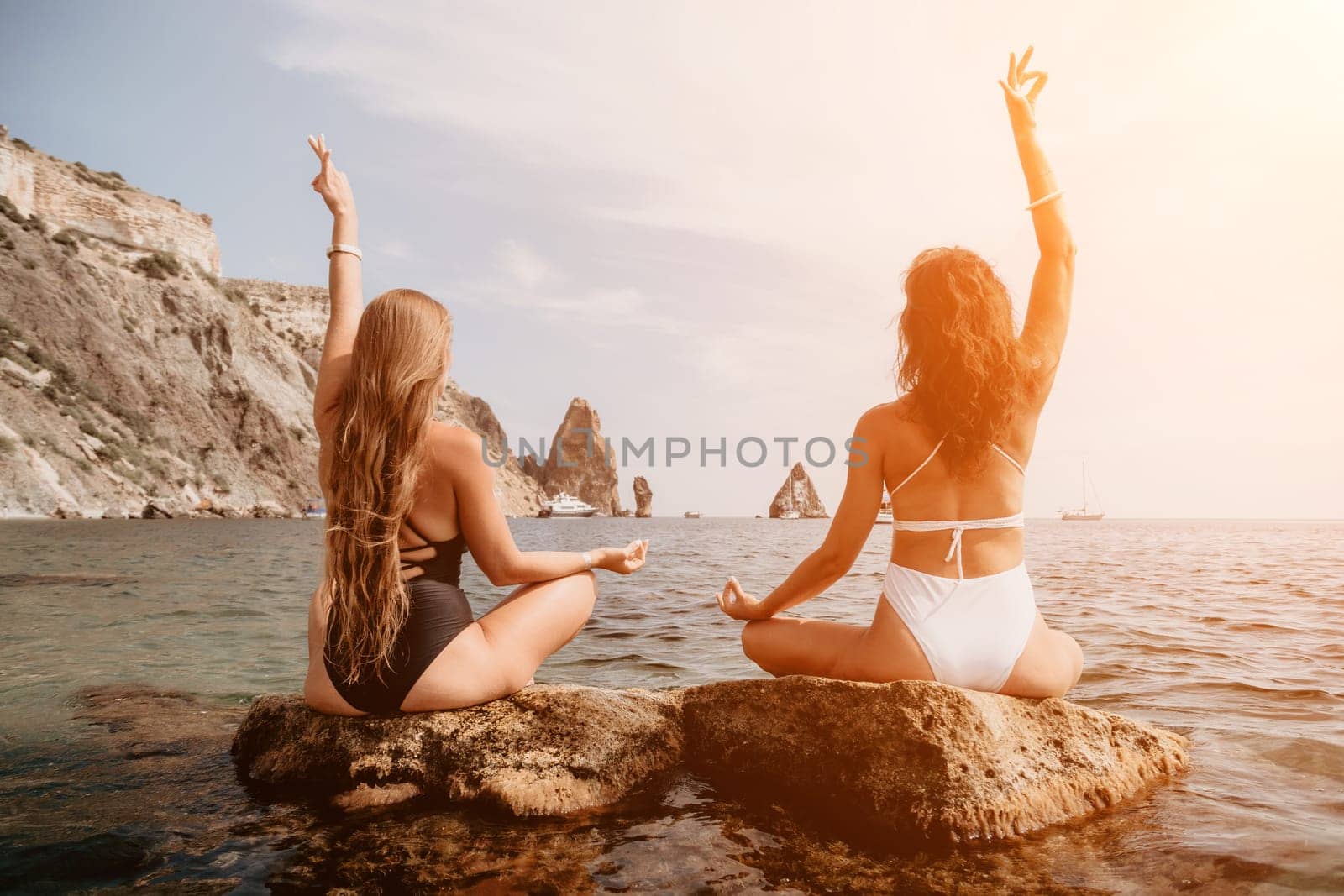 Woman sea yoga. Happy women meditating in yoga pose on the beach, ocean and rock mountains. Motivation and inspirational fit and exercising. Healthy lifestyle outdoors in nature, fitness concept. by panophotograph