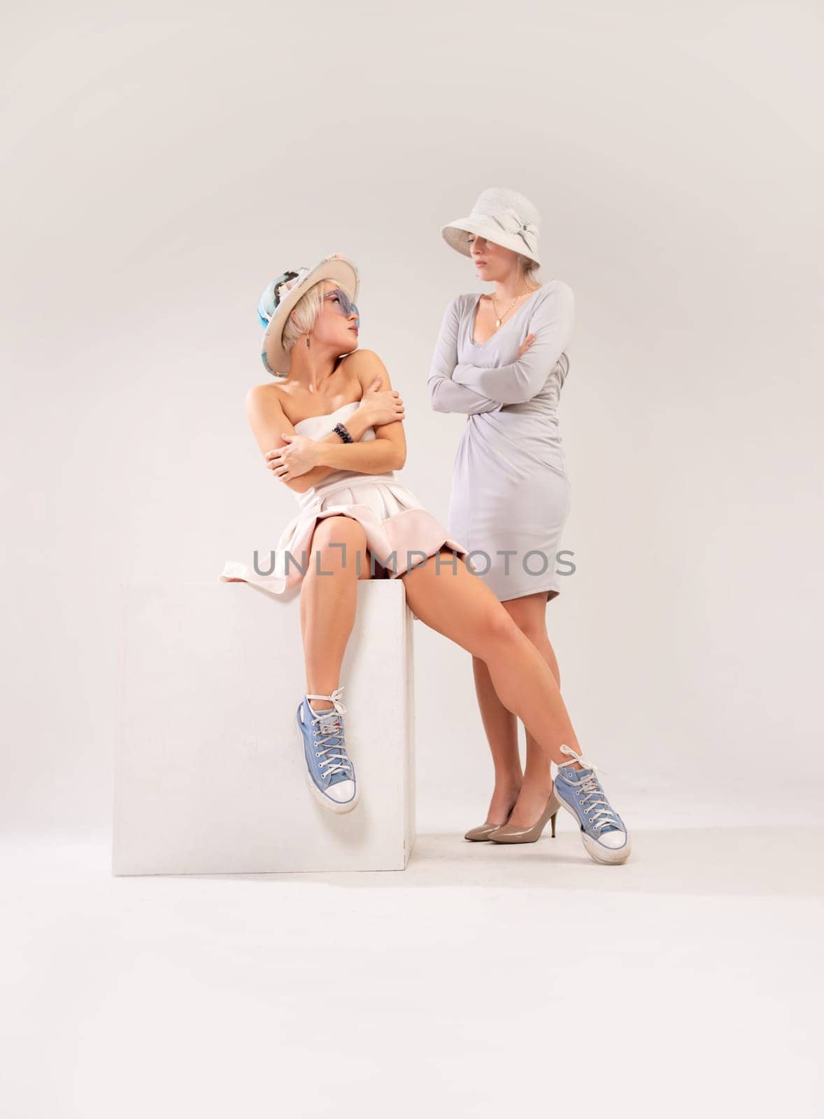 two girls in different styles of clothing playing a conflict or quarrel with each other on a white background, the psychology of human relations, the conflict of the inner child and parent