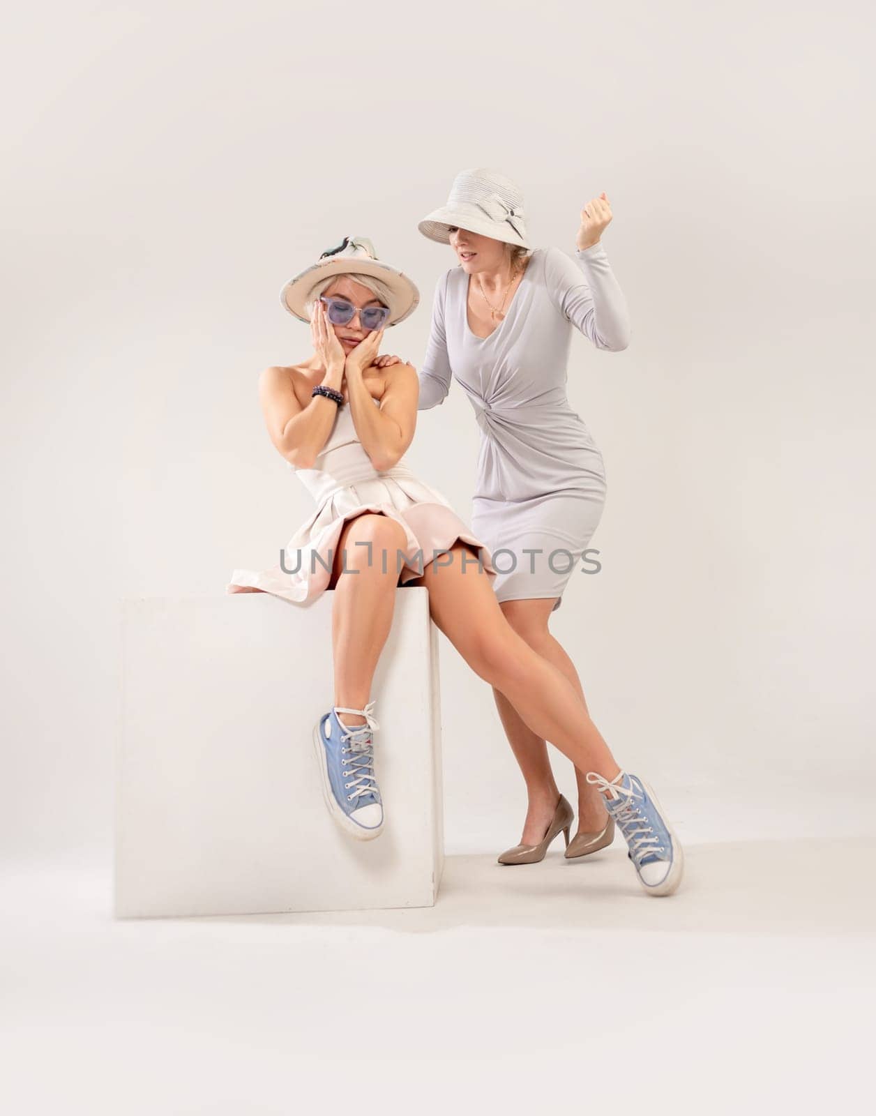 two girls in different styles of clothing playing a conflict or quarrel with each other on a white background, the psychology of human relations, the conflict of the inner child and parent