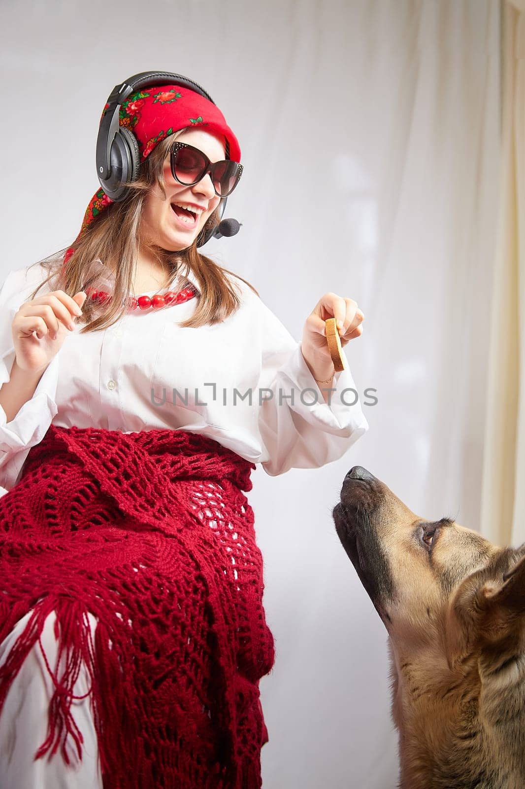 Young girl in red scarf, large headphones with microphone and black glasses and big shepherd dog. Woman who is radio or television presenter, female telecom operator, blogger, Freelancer and animal by keleny