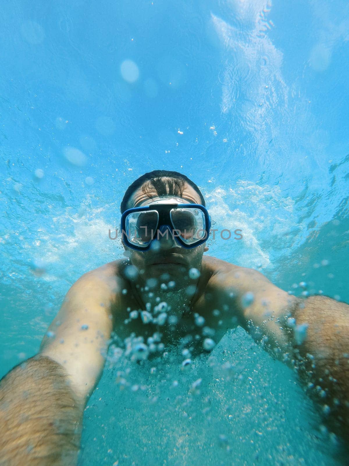 Swimmer in goggles dives under the water, raising splashes. High quality photo