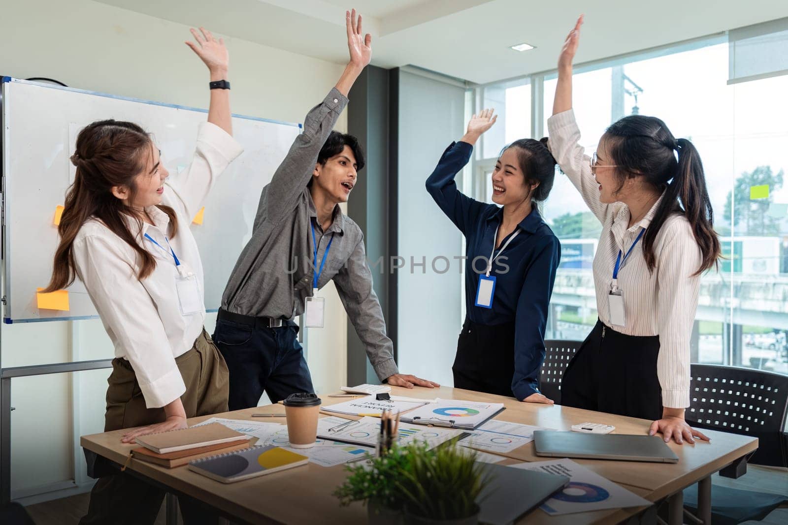 Business team celebrate corporate victory together in office, laughing and rejoicing, smiling excited employees colleague screaming with joy in office.