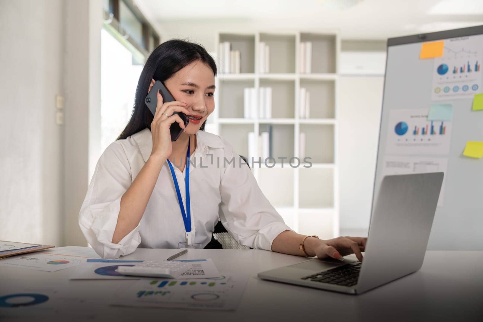 Young woman business laughing while talking on cellphone in office.