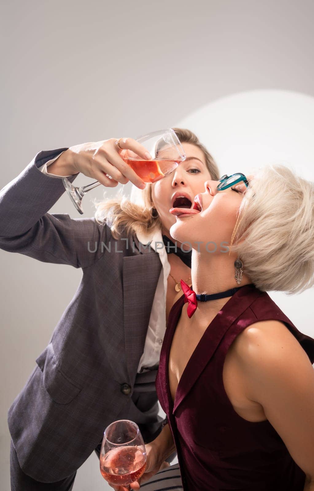 two close girlfriends with glasses of alcohol having fun laughing at a party in the studio on a white background copy paste