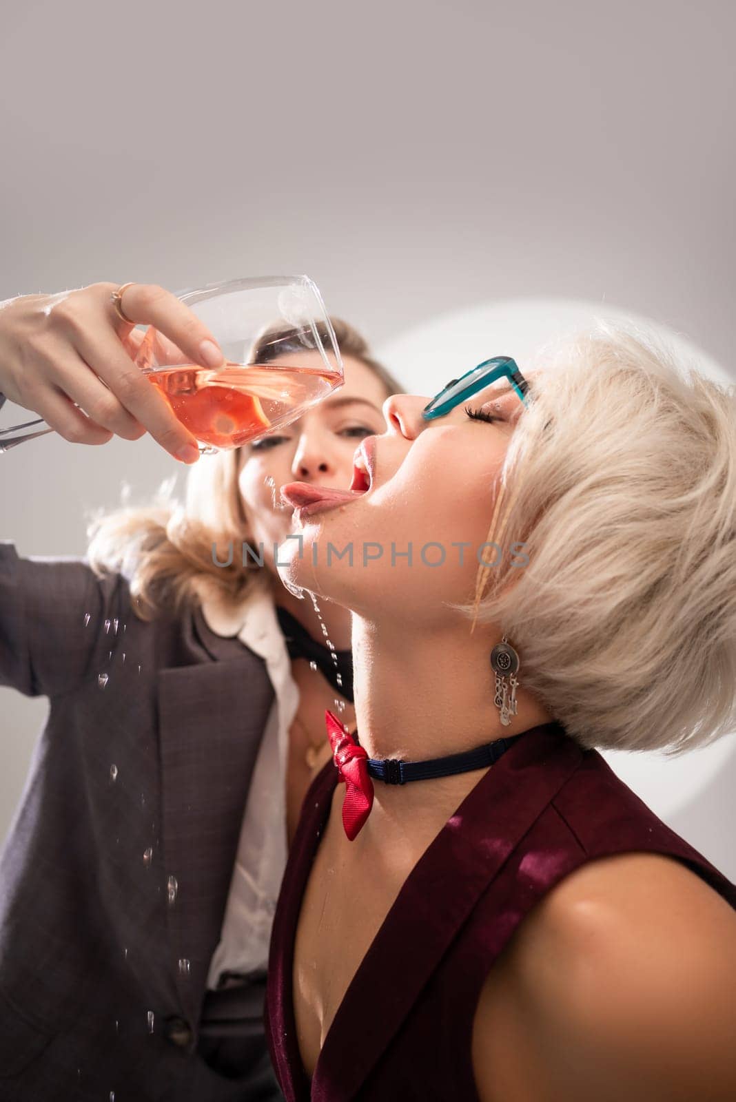 two close girlfriends with glasses of alcohol having fun laughing at a party in the studio on a white background copy paste