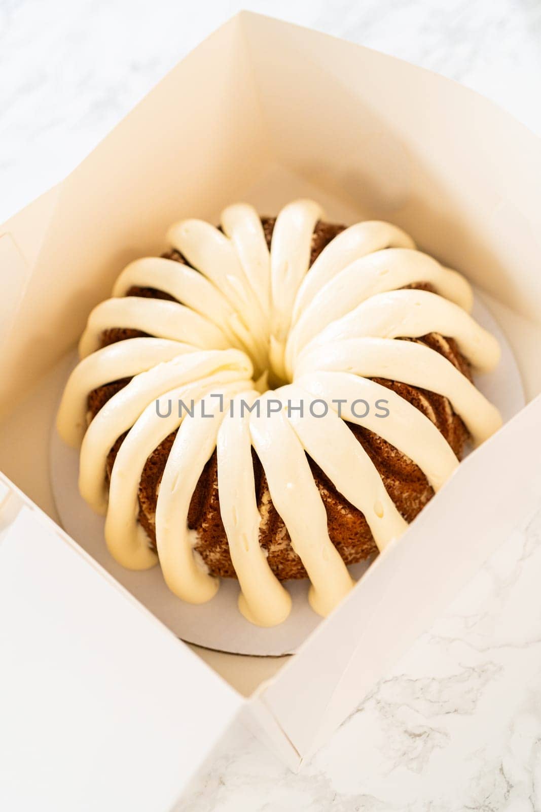 The freshly baked bundt cakes are carefully nestled into white paper boxes, preparing them for secure transportation while maintaining their delectable appearance.