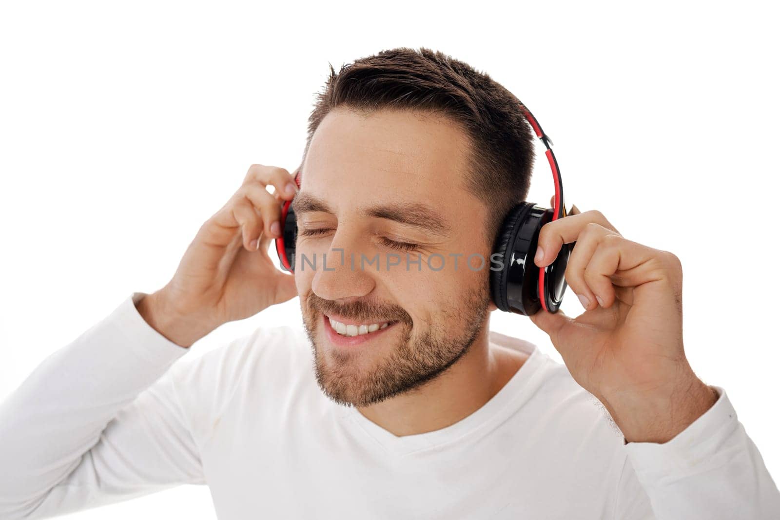 Close-up portrait of handsome young man in headphones listening to music and dancing isolated on white background.