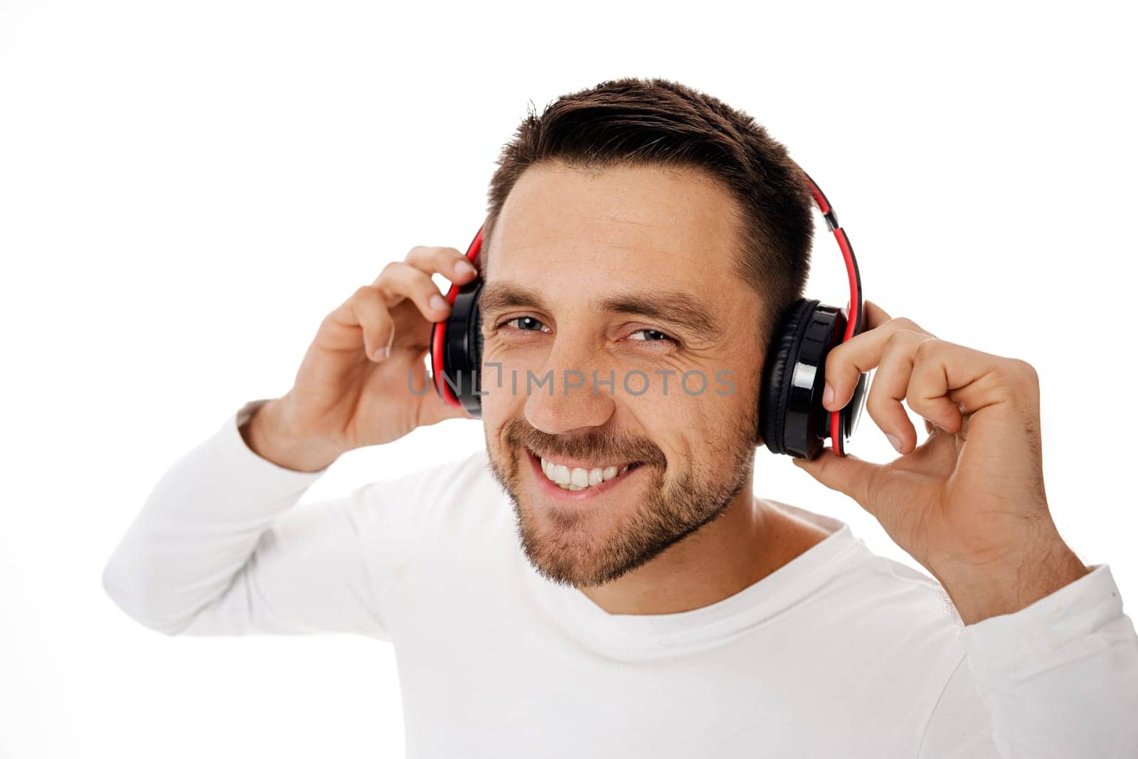 Close-up portrait of handsome bearded young man in headphones listening to music and dancing isolated on white background.