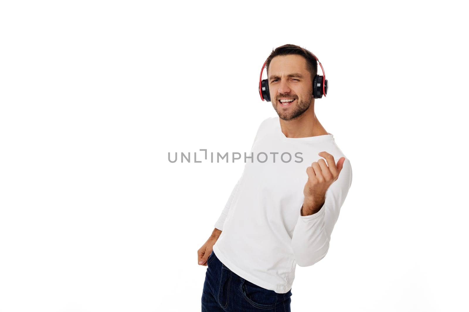 handsome young man in headphones listening to music and dancing isolated on white background.