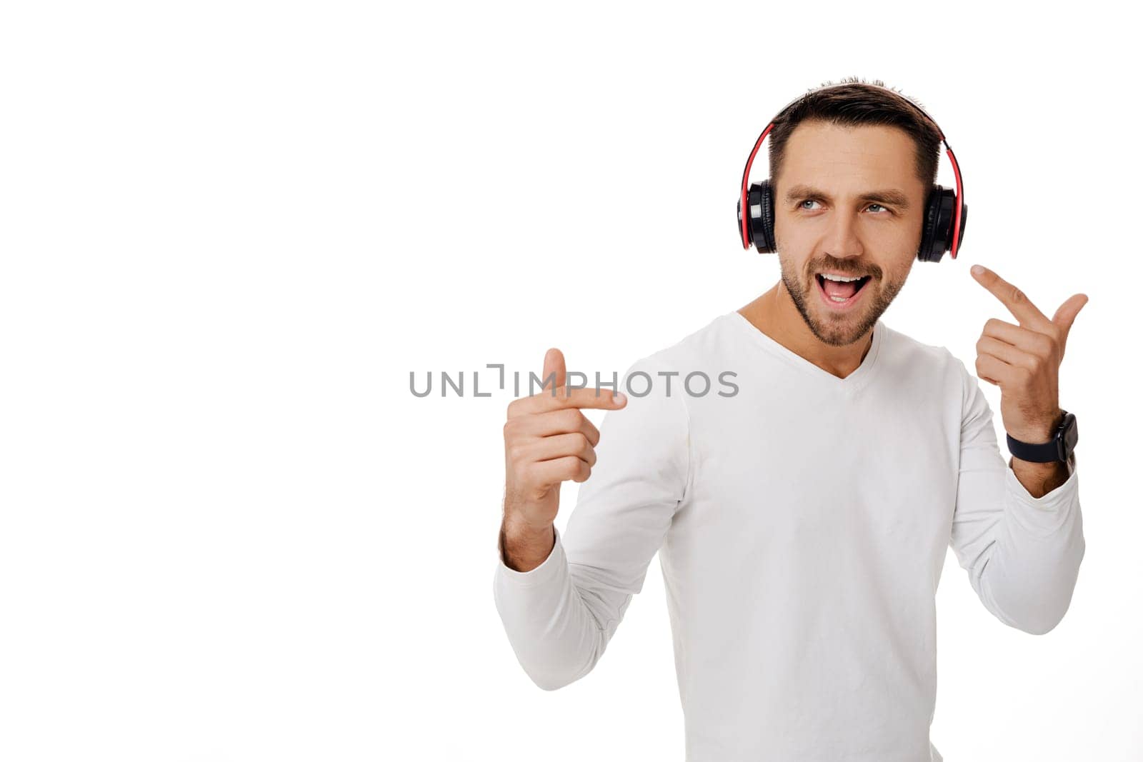 handsome smiling bearded young man in headphones listening to music, dancing and singing isolated on white background.