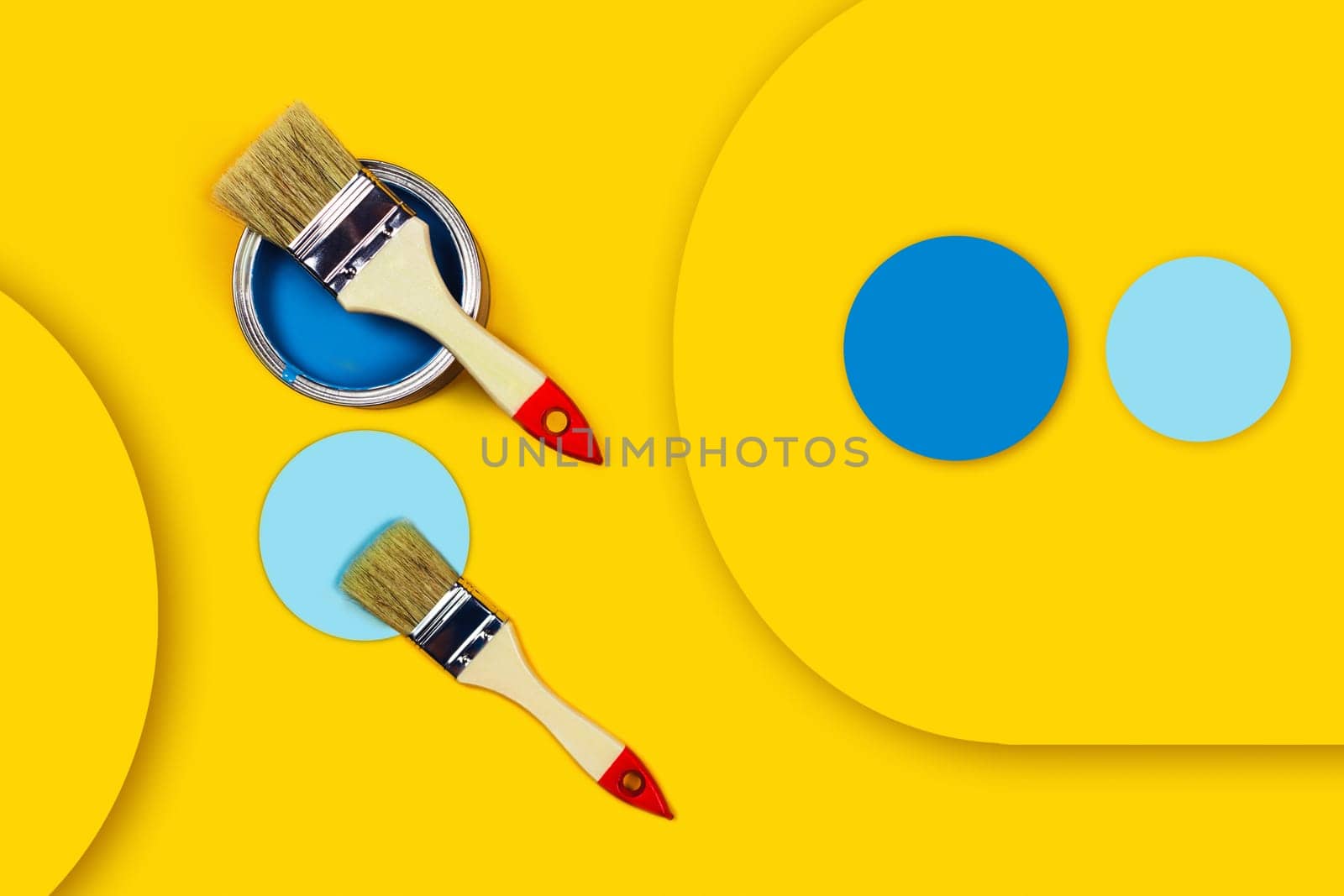 Renovation concept. Yellow background with blue paint jar and two brushes with blue circle. Flat lay, top view, copy space.