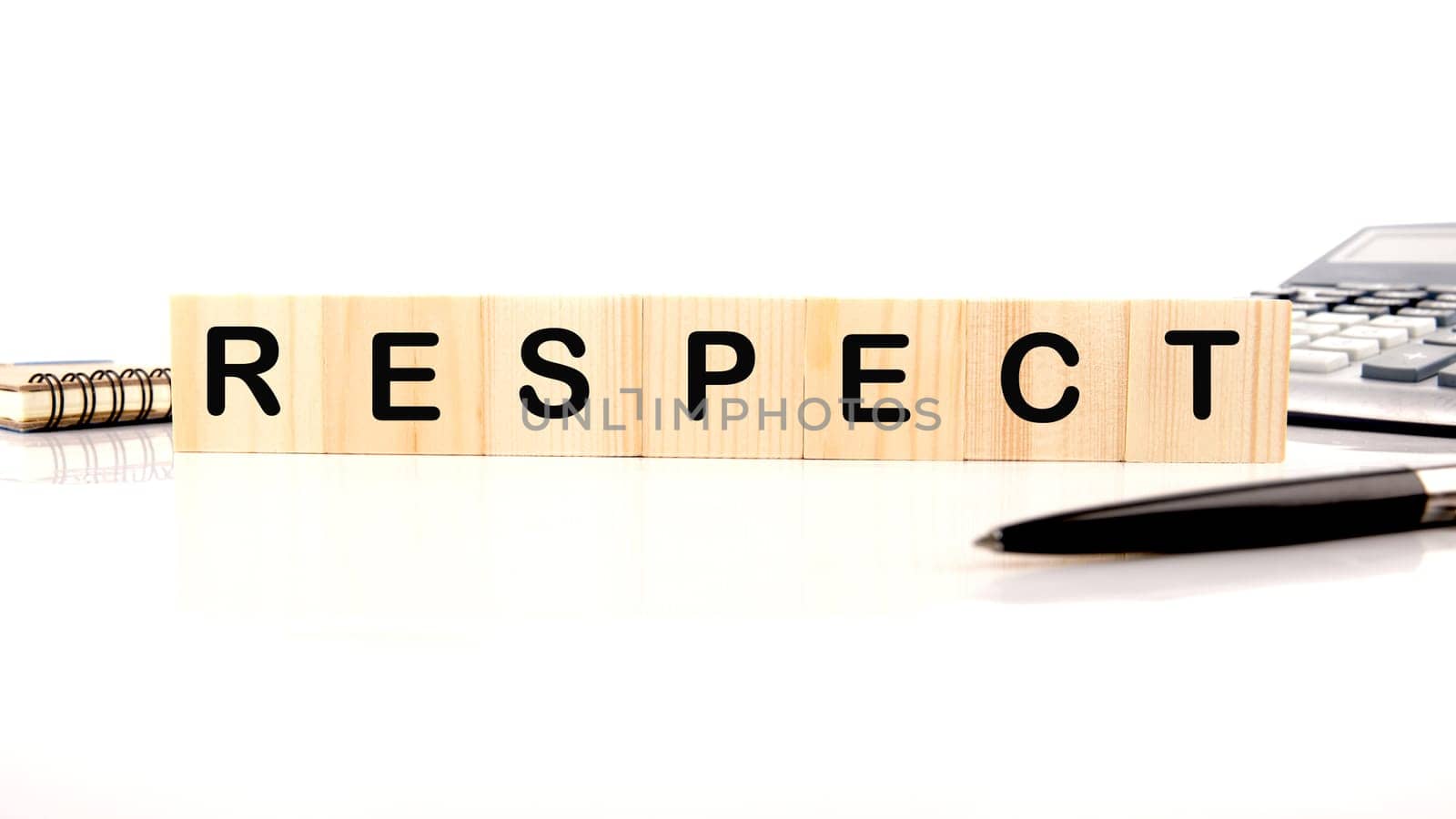 respect word assembled from wooden cubes next to a calculator, pen and notepad by Ihar