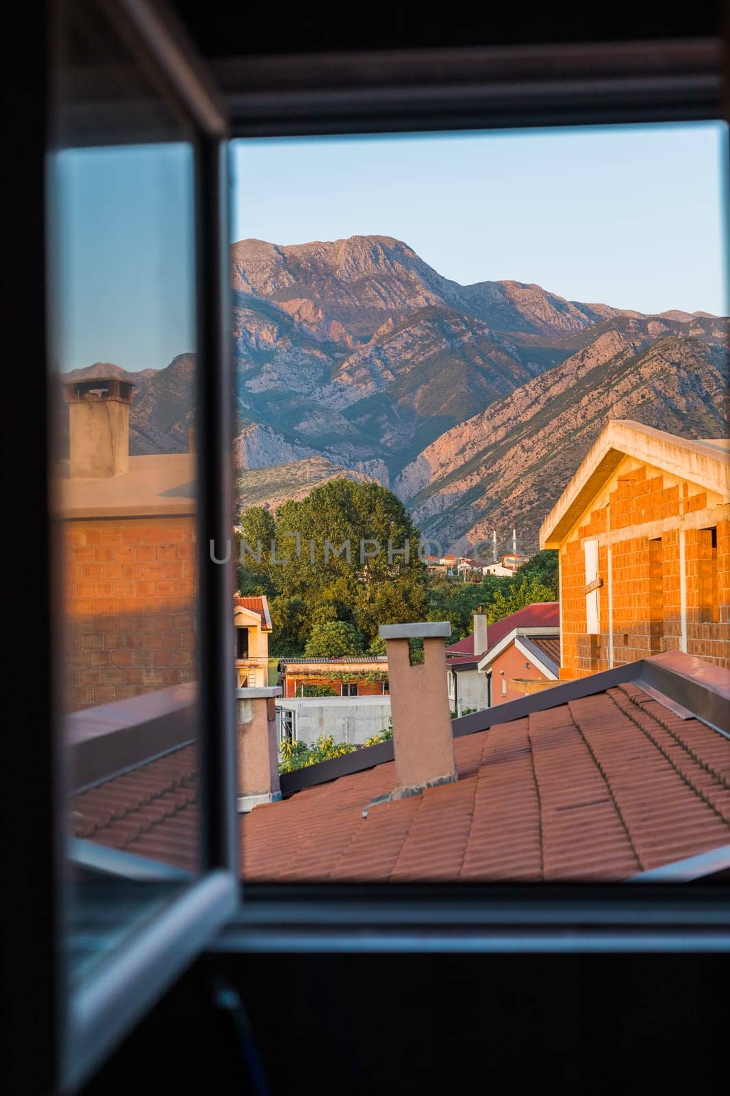 View from window a small village with mountain houses on the mountain crest in Bar city Montenegro. Sunset.