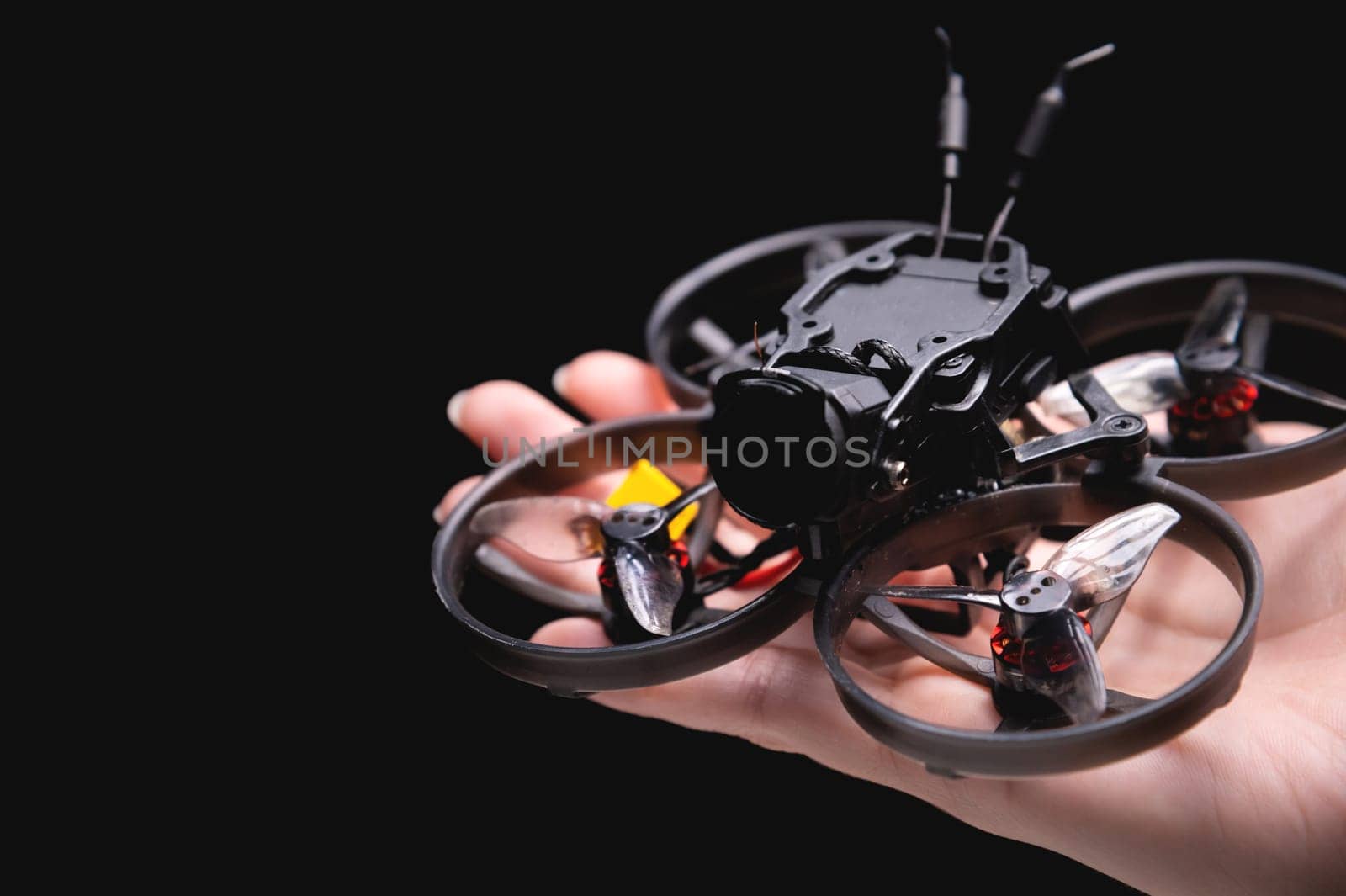 Hands holding a racing drone with a camera. Woman holding a radio-controlled mini quadcopter.
