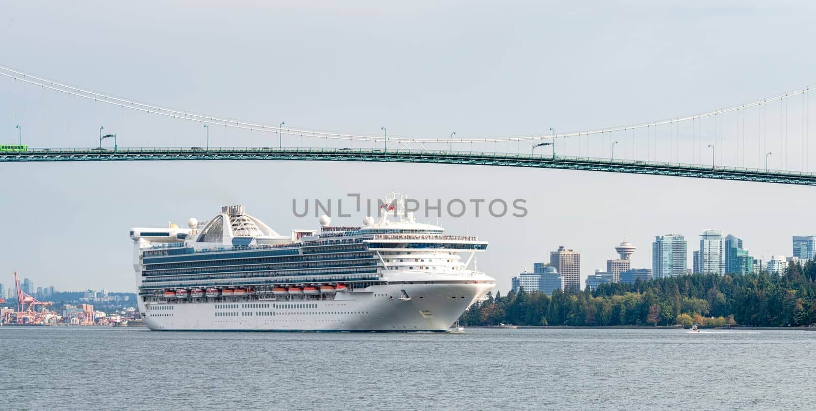 Huge white ocean cruise liner passing famous Lion Gates Bridge in Vancouver, Canada