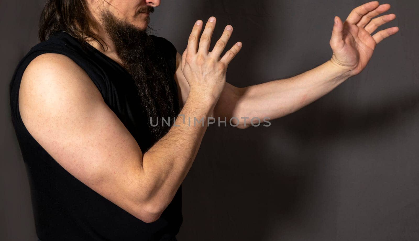 Sporty young man training against dark gray background. a man shows a wushu kick, a beautiful man's hand, Mockup for tattoos, jewelry, mehendi