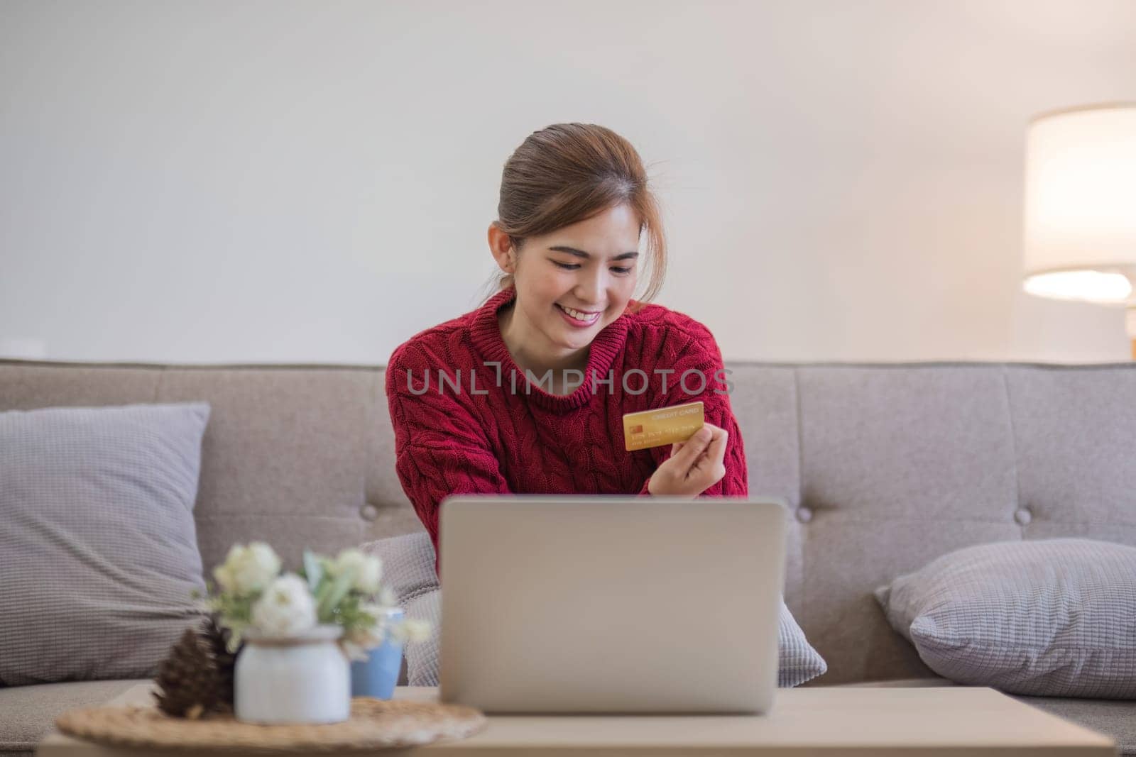 online shopping. Woman buying laptop using credit card sitting on sofa at home.